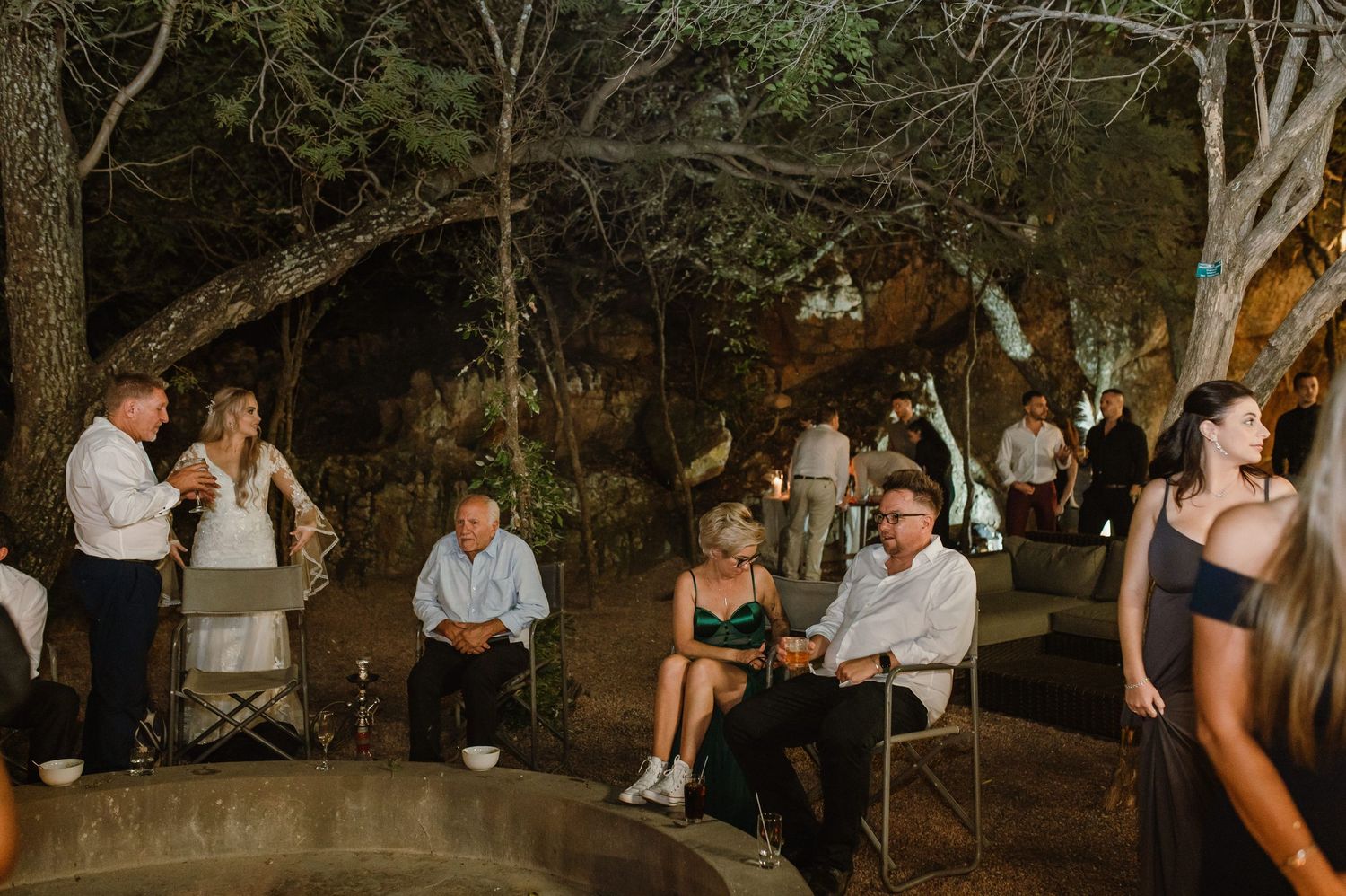 Wedding guests relaxing in casual outdoor seating area during evening celebration.