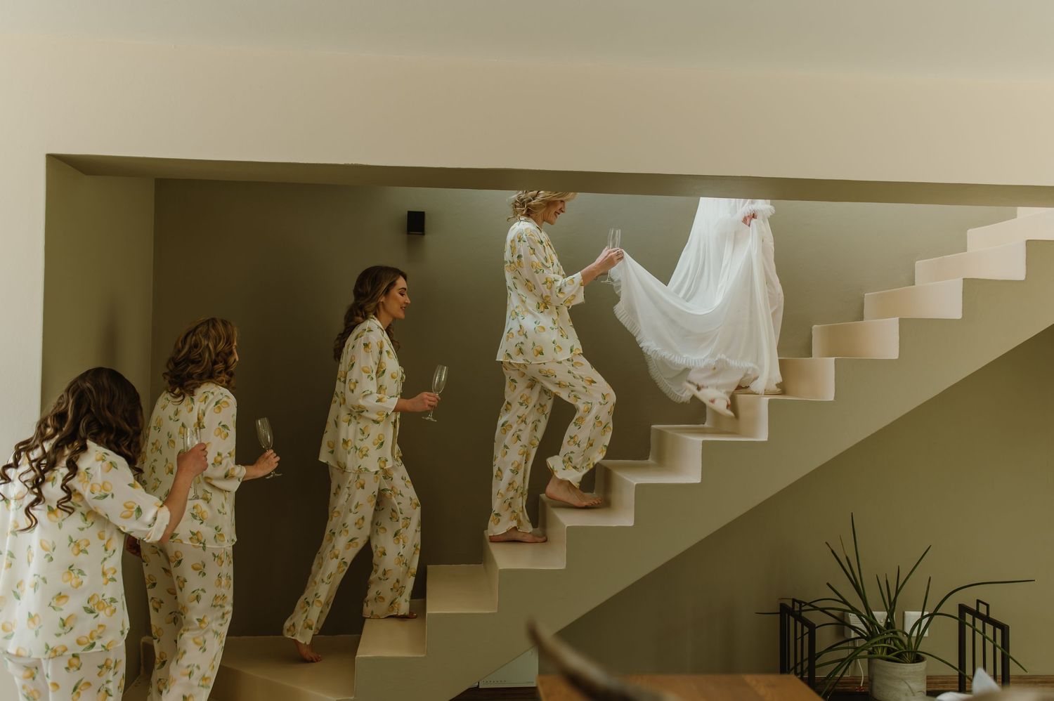 Wedding party walking up stairs in floral robes during pre-ceremony preparations.
