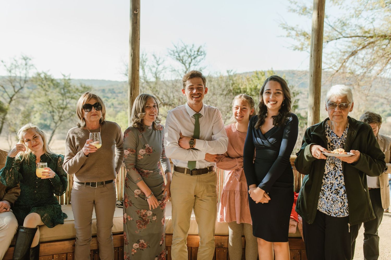 Joyful wedding guests celebrating with drinks at outdoor reception.