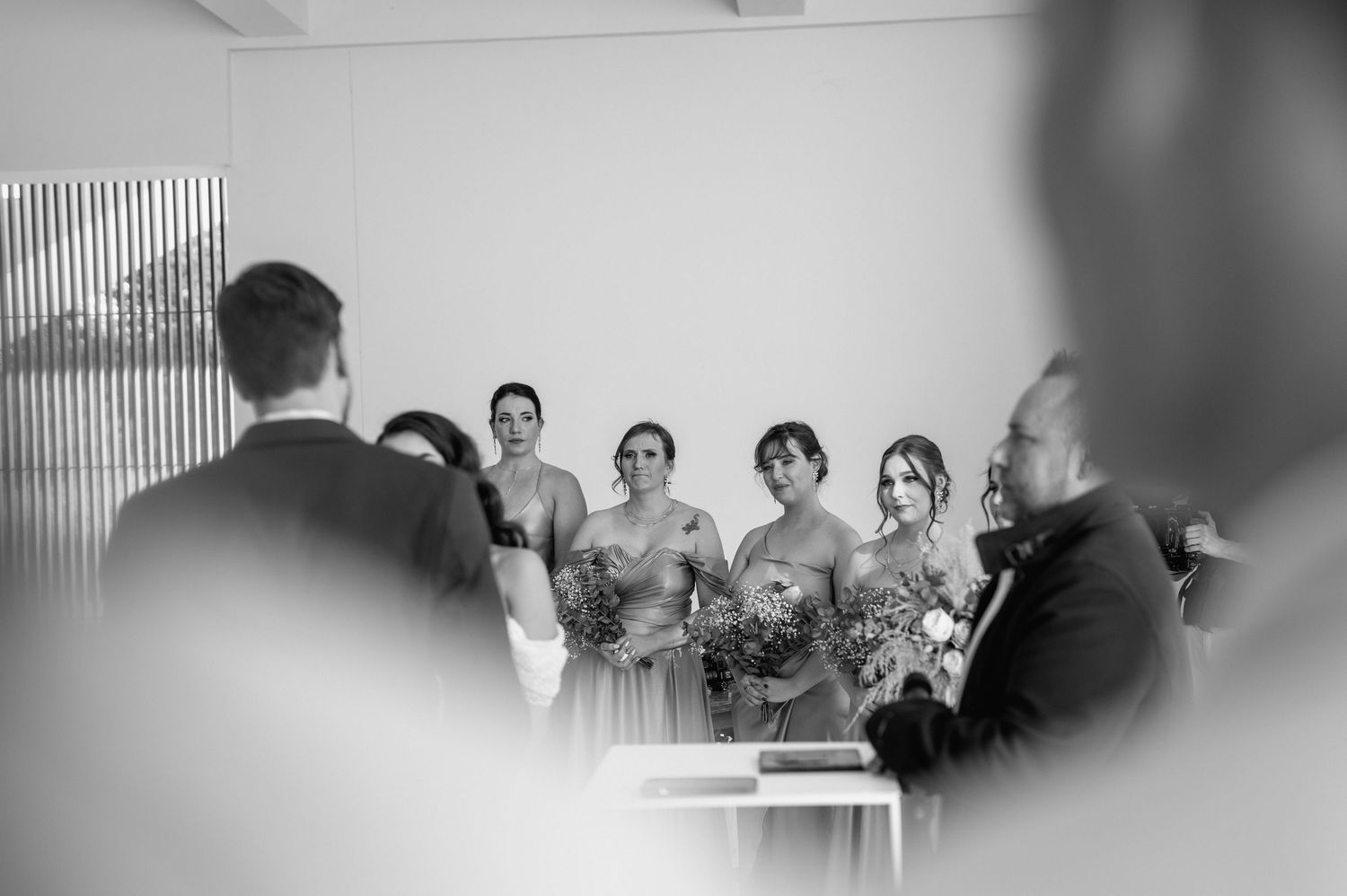 Black and white artistic shot of wedding ceremony reactions in a modern venue.