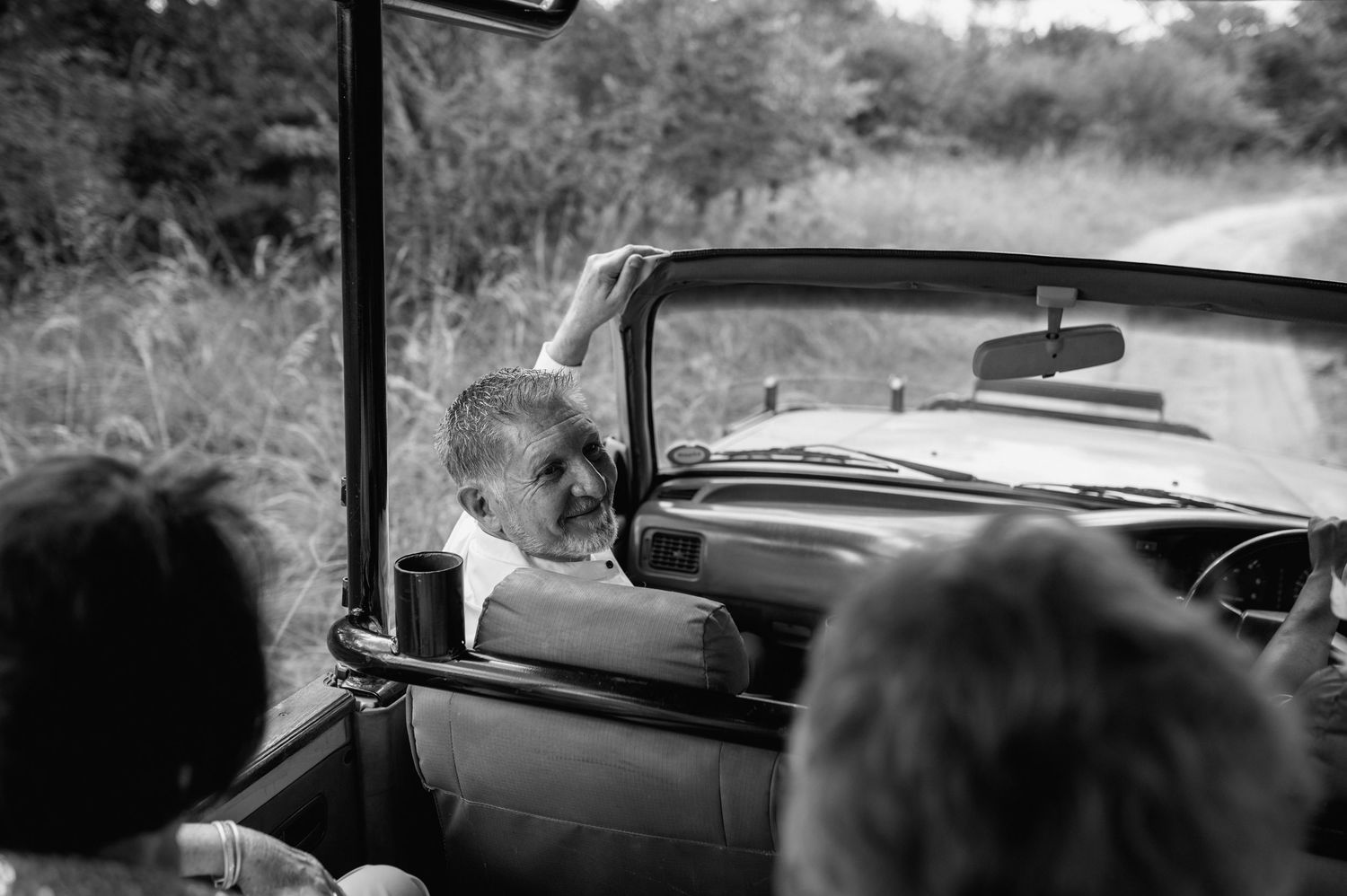 A black and white photo of people riding in a classic convertible car.
