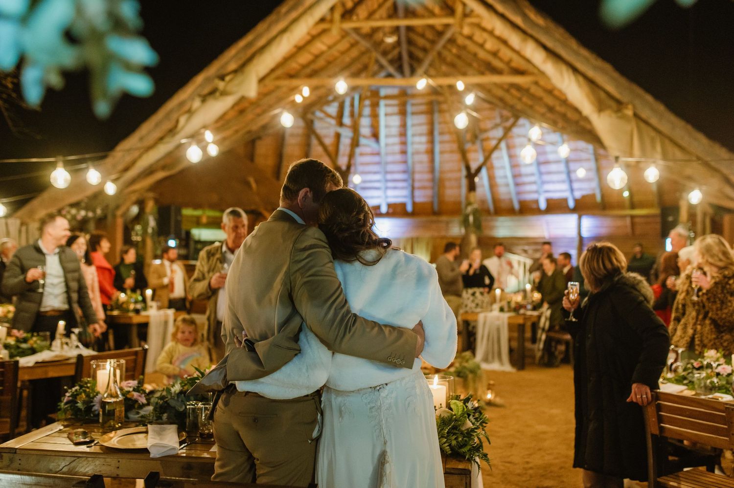 Evening wedding celebration in a rustic barn venue decorated with string lights and natural elements.