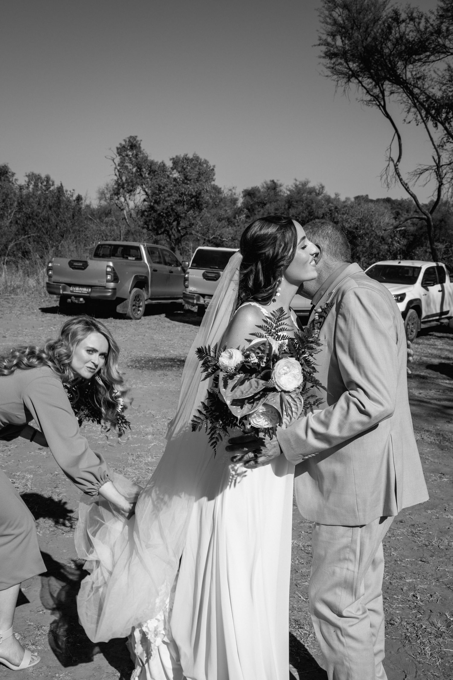 Romantic wedding couple sharing a tender moment outdoors in black and white photography.