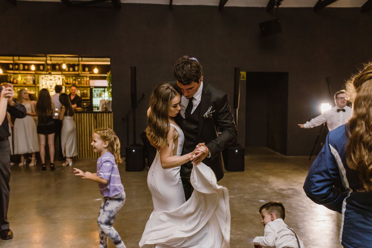 People dancing in formation at an indoor event with atmospheric lighting.