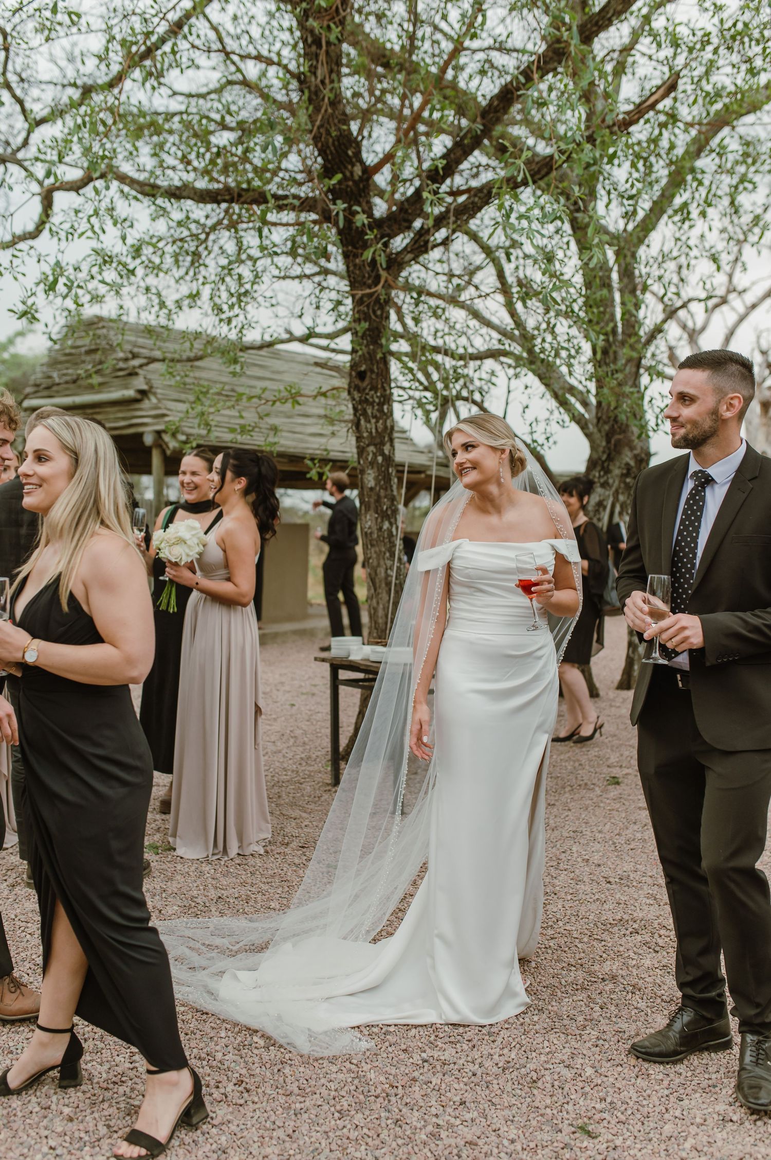 Wedding party celebrating and dancing outdoors at rustic venue.