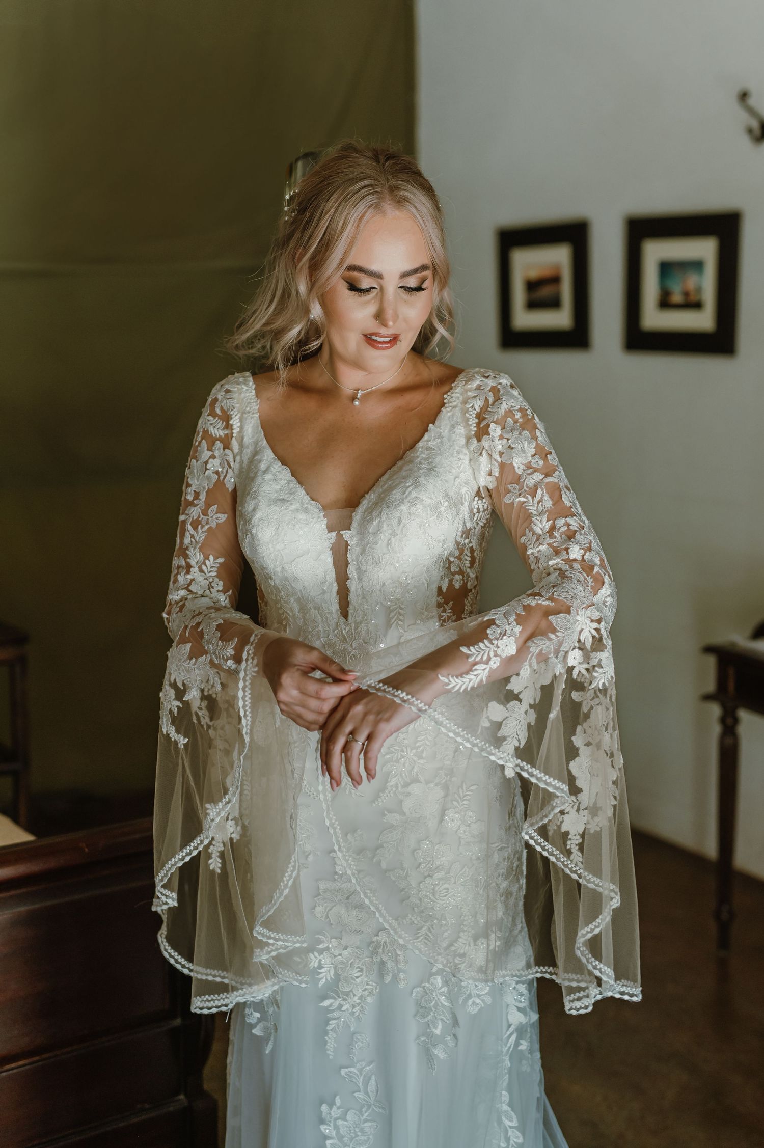Full-length view of a romantic wedding gown with sheer lace sleeves and plunging neckline.