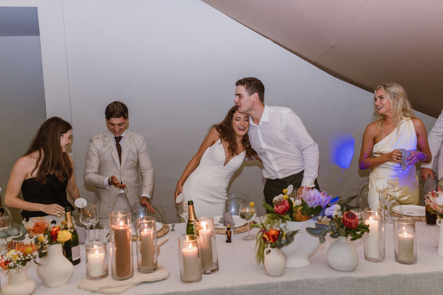 Elegant table settings with mason jar centerpieces and candles at a wedding reception.