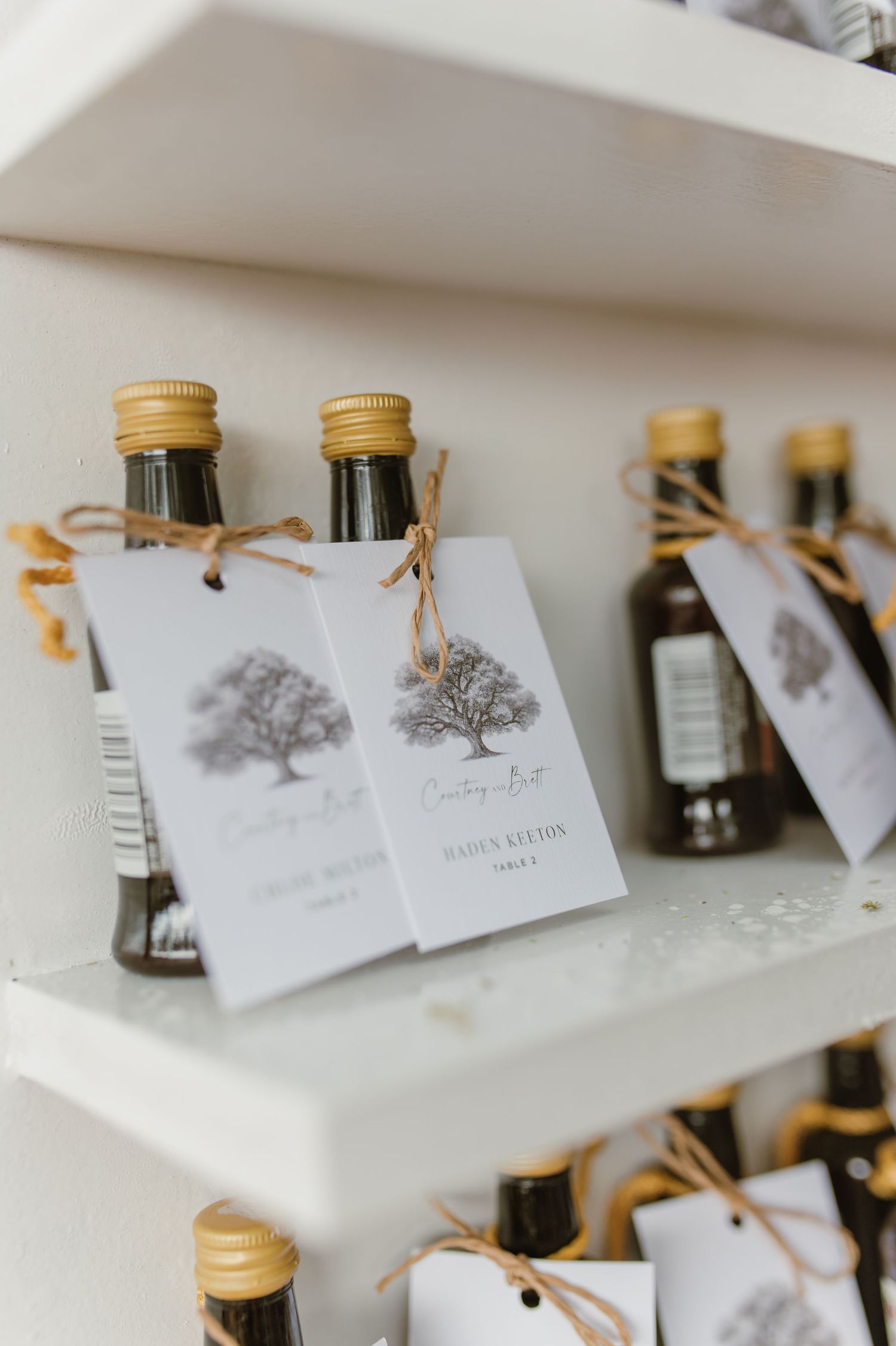 Small bottles with gold caps and tree-themed tags arranged in a neat display.