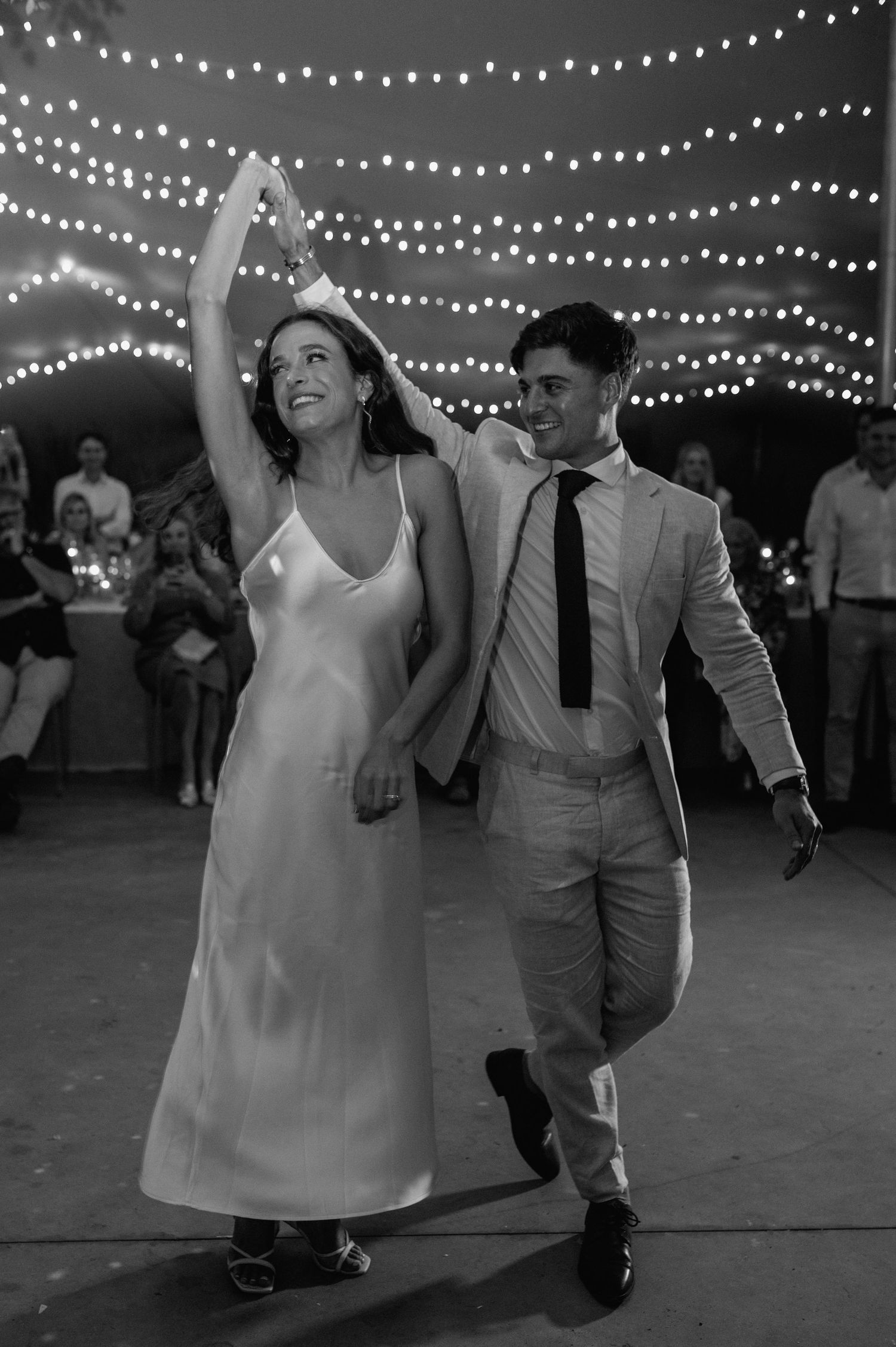 Black and white capture of a dancing couple under twinkling reception lights.