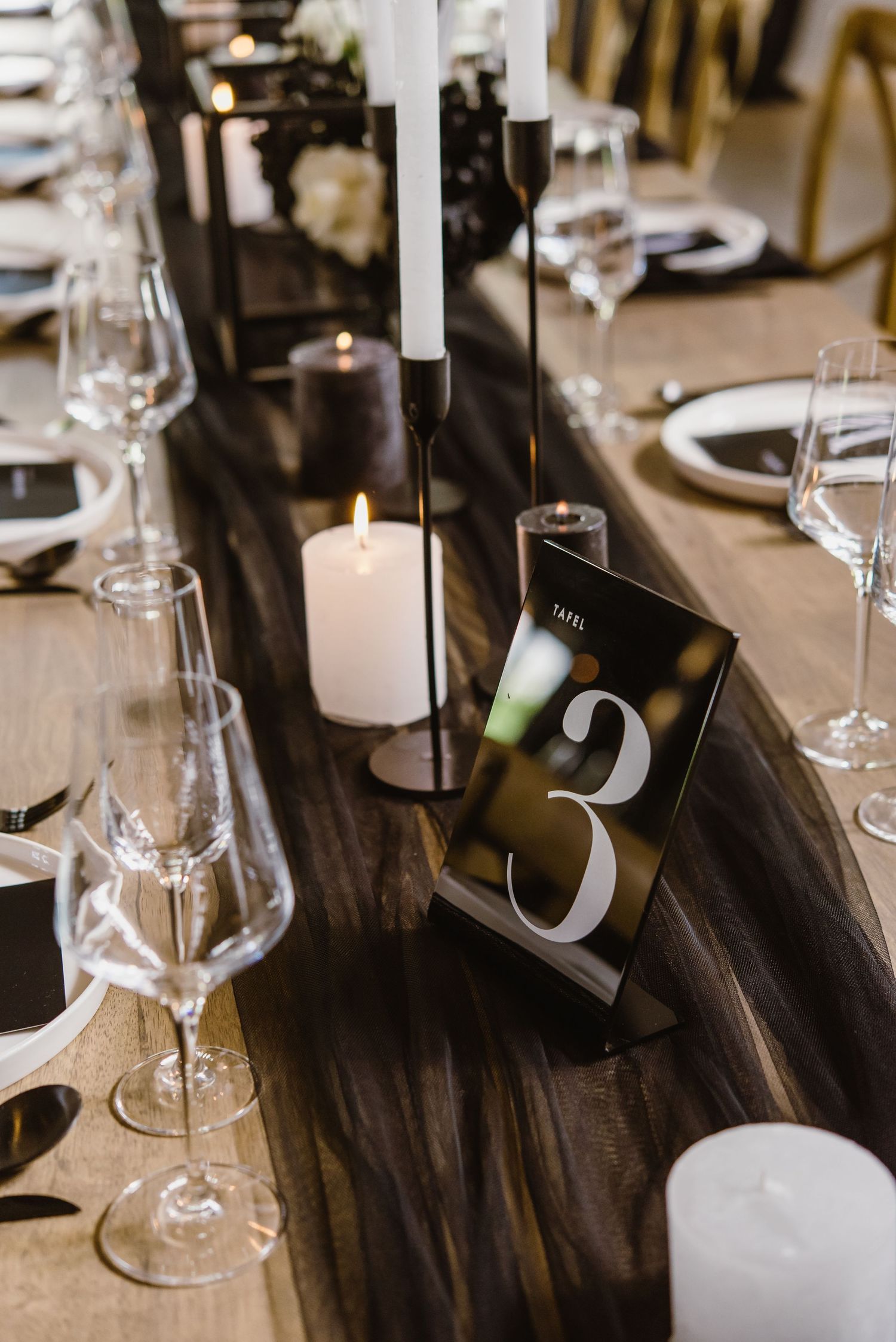 Elegant table setting with wine glasses, candles and table numbers for an upscale event.