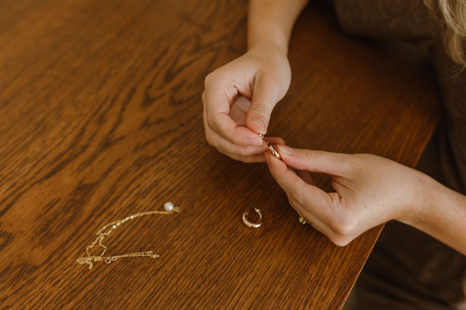 A series of hands arranging small white flowers on a wooden surface in a delicate pattern.