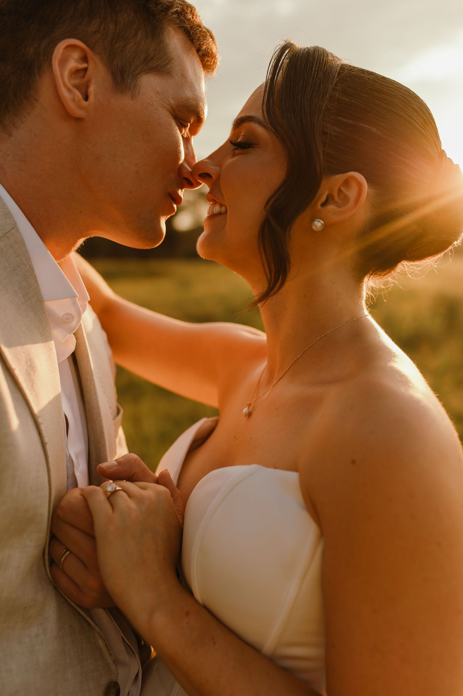An intimate wedding portrait captured in warm sunset lighting with a dreamy golden glow.