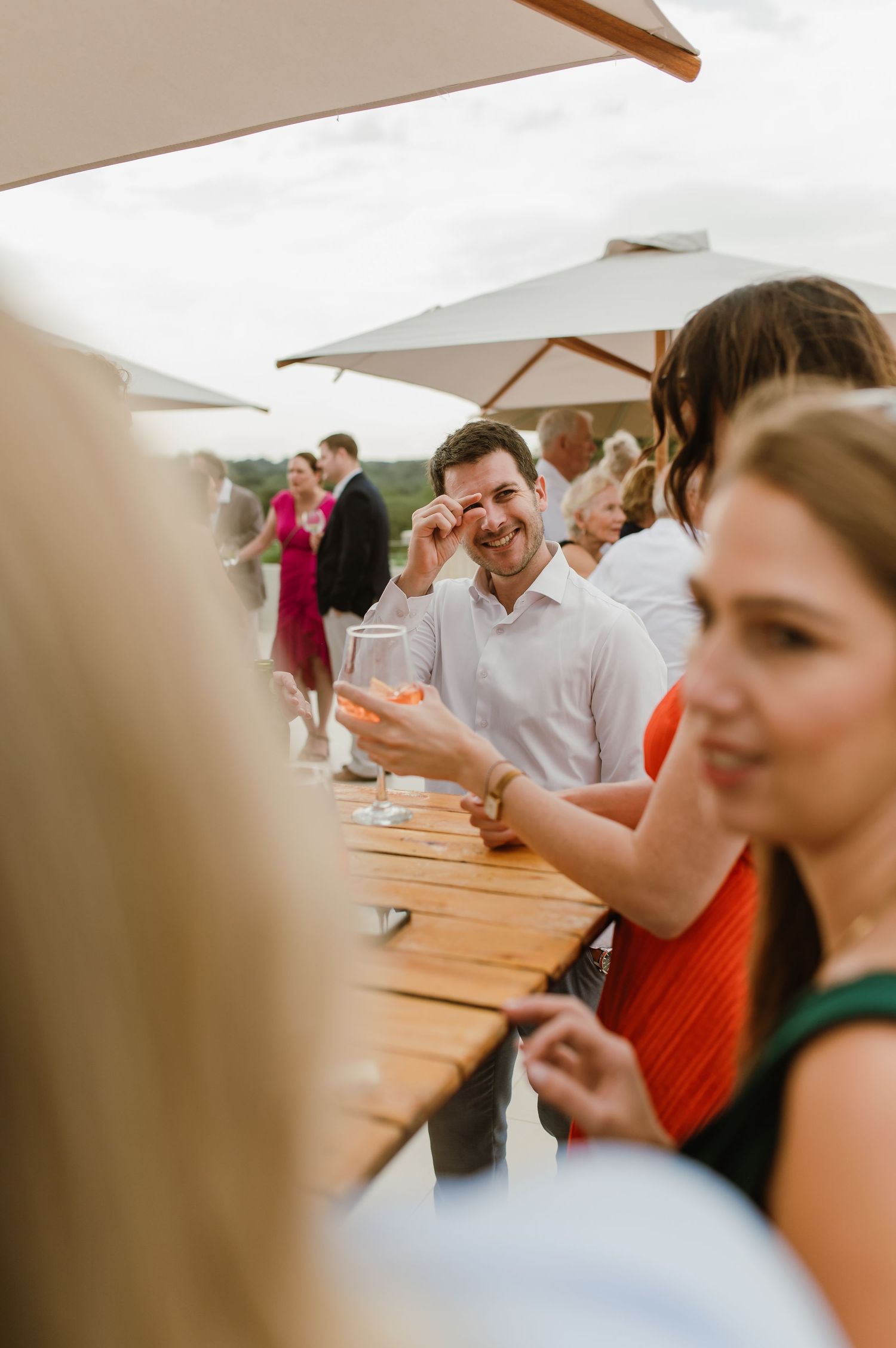 Candid moments of guests enjoying themselves at an outdoor wedding reception under a tent.