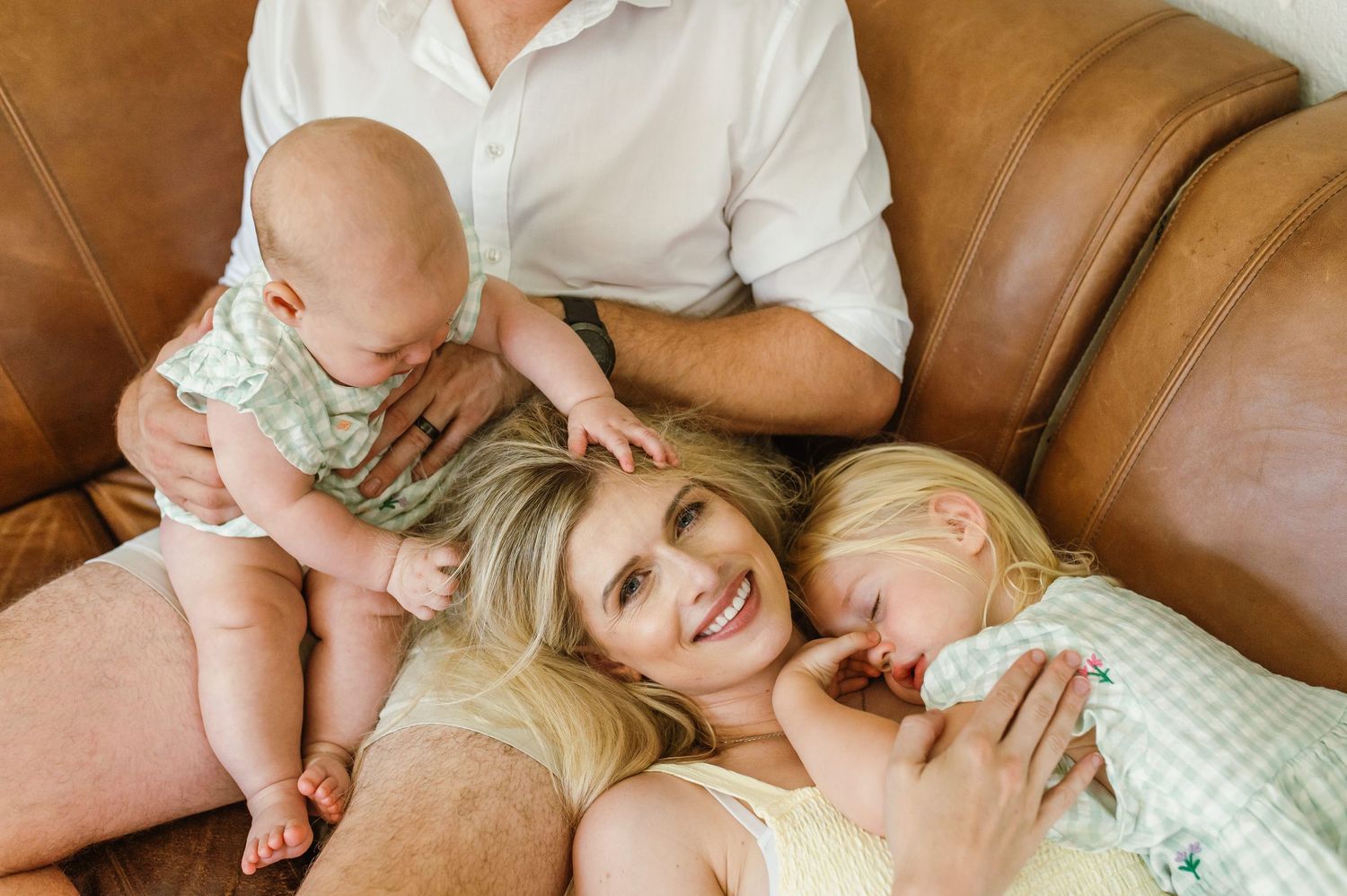 A series of candid lifestyle photos showing tender moments between parent and child on a brown leather couch.
