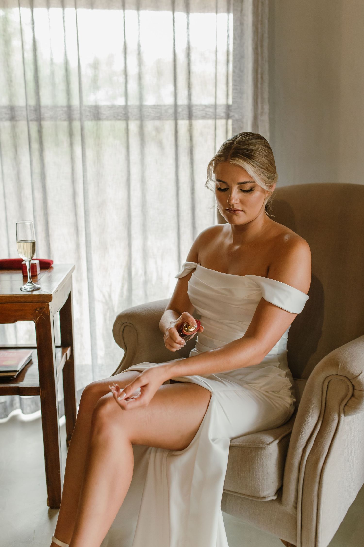 Elegant bridal preparation moment showing white dress details in a sunlit room.
