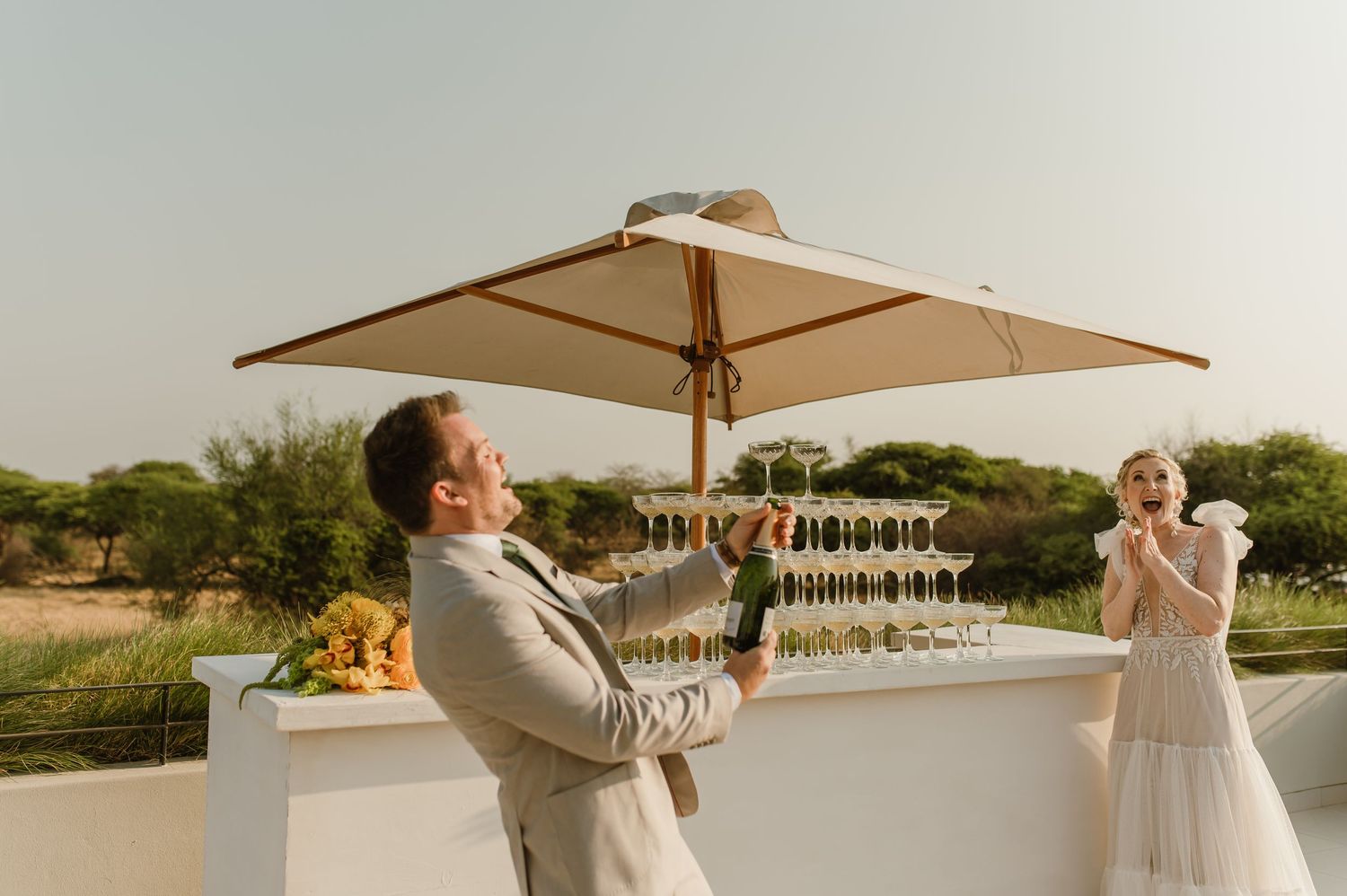 Wedding celebration on a modern white terrace with wooden umbrellas.