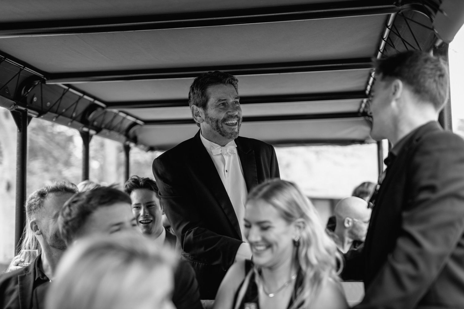 Wedding guests sharing joyful moments inside a safari vehicle during transportation.