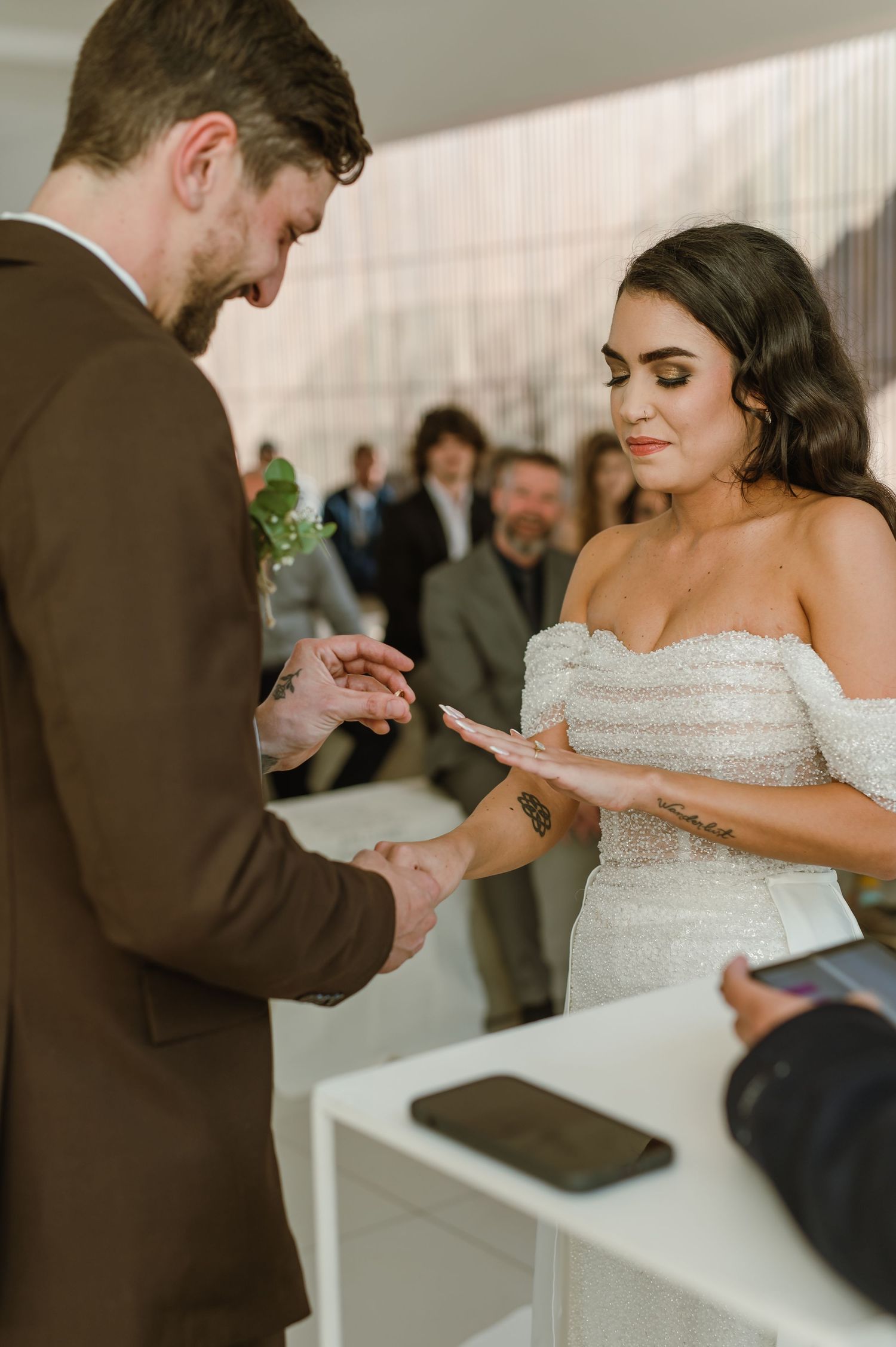 Intimate moment during ring exchange at modern indoor wedding ceremony.