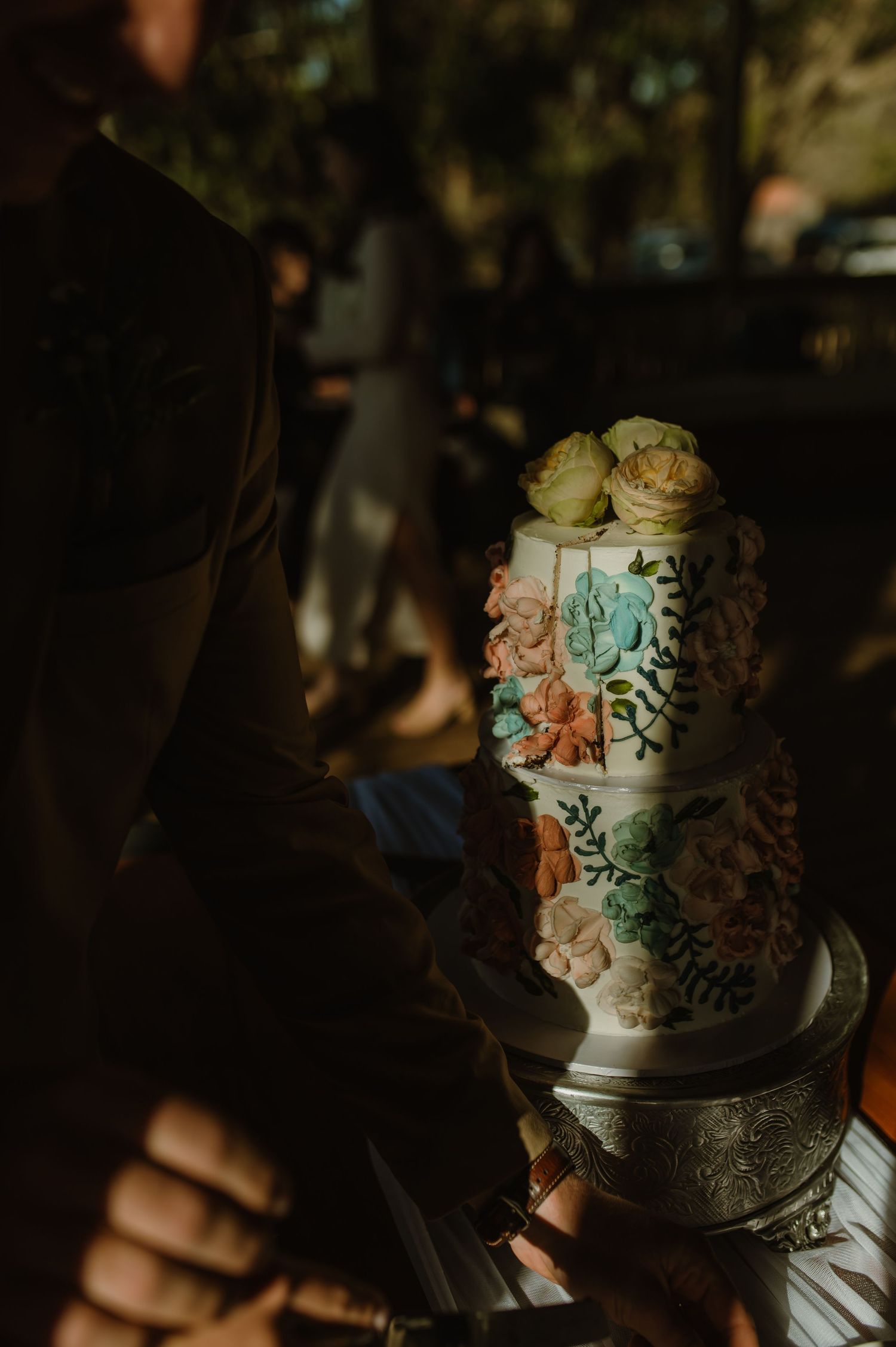 Elegant wedding cake with delicate floral designs in coral and mint green colors.