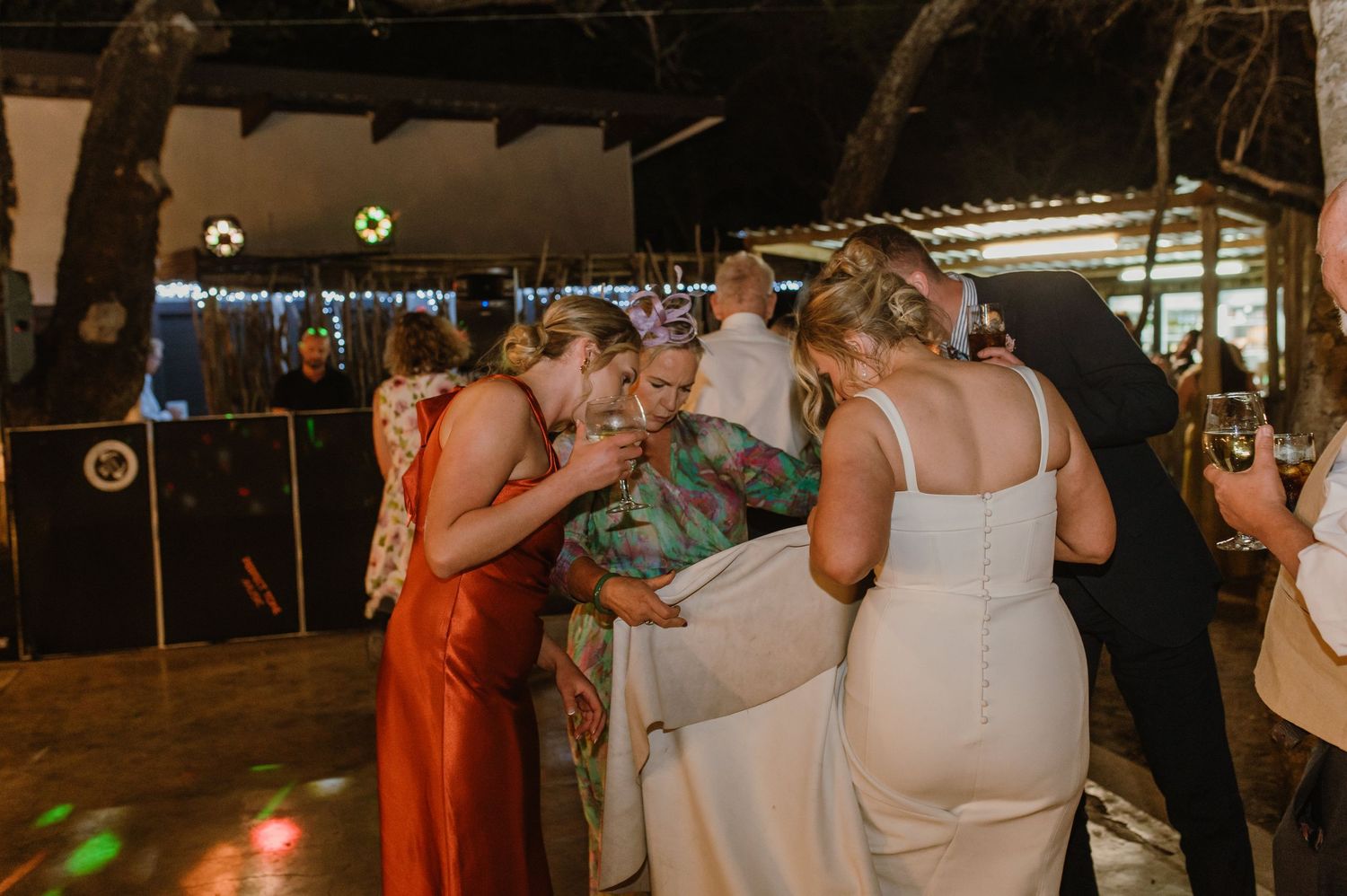 Wedding guests dancing and socializing at an evening reception under string lights.