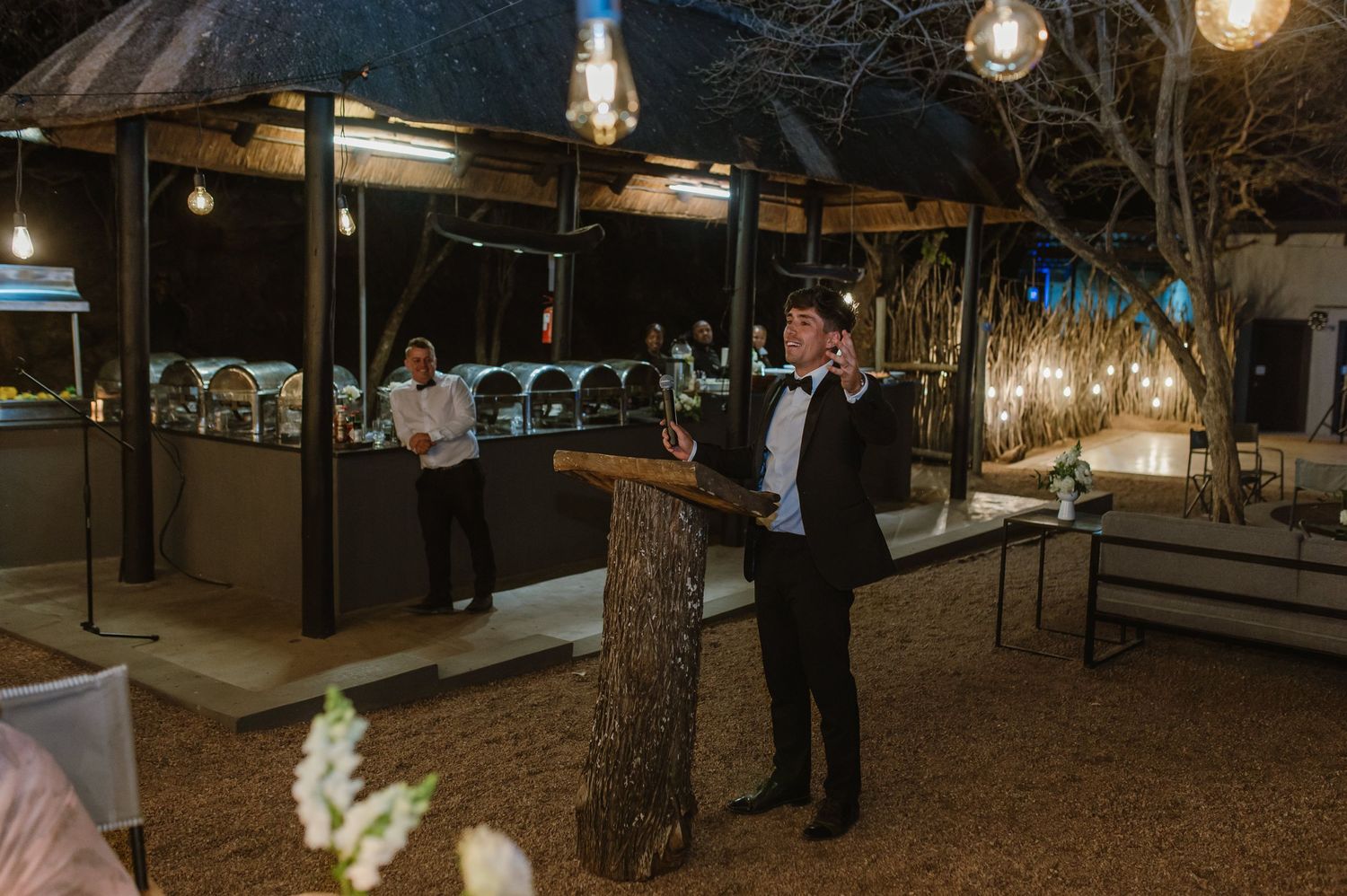 Outdoor wedding venue illuminated with string lights and lanterns creating a magical atmosphere.