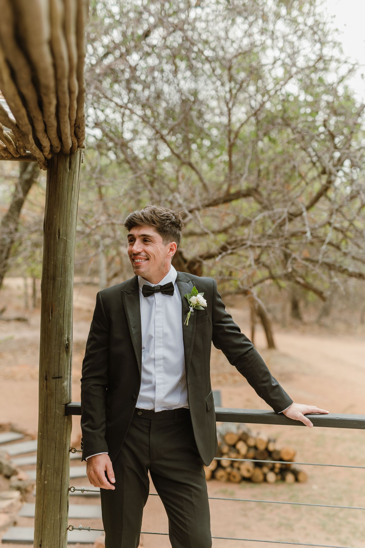 Outdoor portrait on a rustic porch wearing formal attire with natural scenery in background.