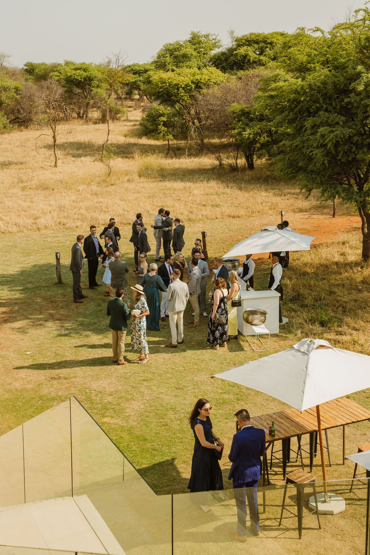 Outdoor gathering with white umbrellas and people mingling on grassy terrain.