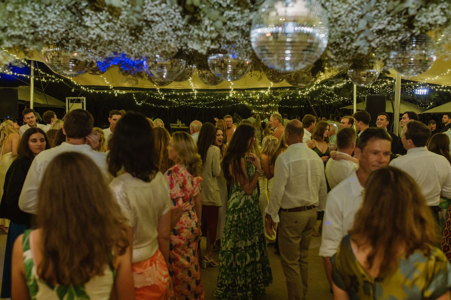 Wedding reception venue with disco balls and string lights illuminating the dance floor.