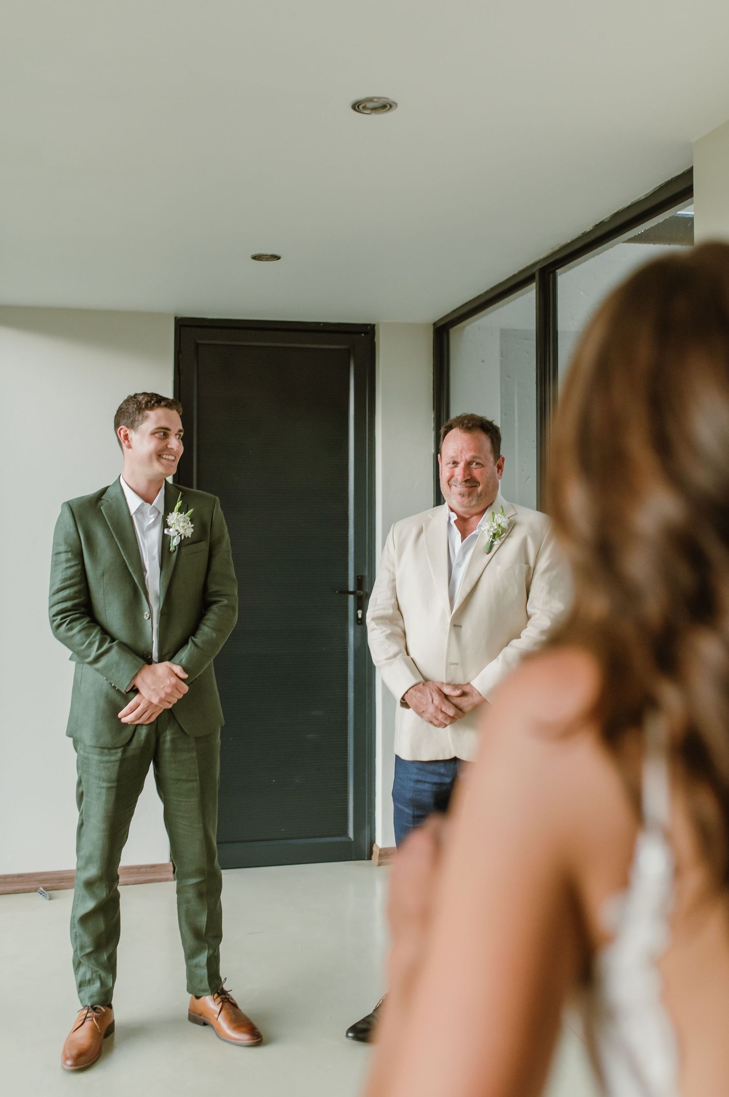 Wedding first look sequence showing reactions through a modern interior doorway.