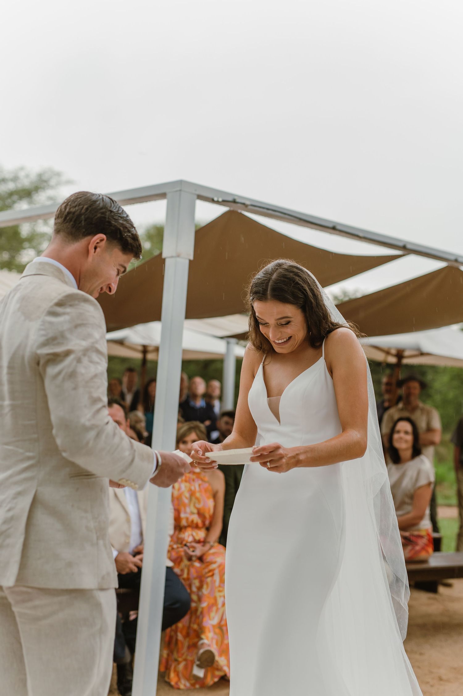 Intimate ring exchange moment during outdoor wedding ceremony under white canopy.