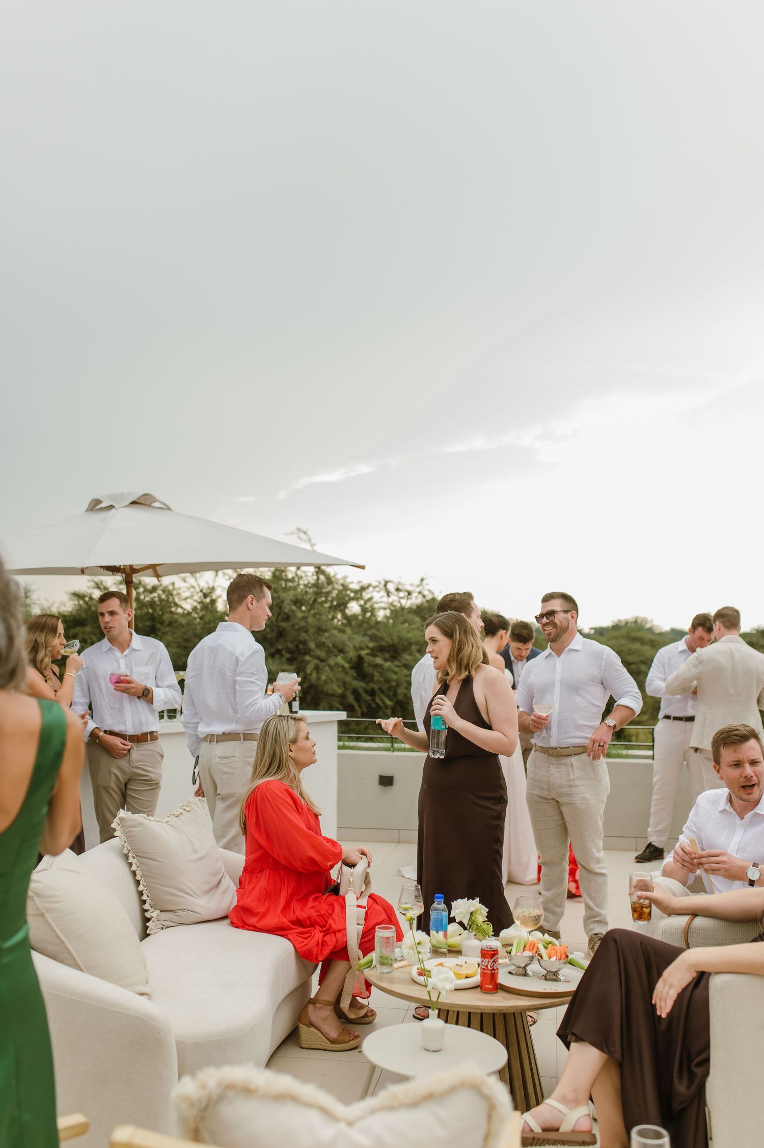 Wedding guests socialize and celebrate at an outdoor rooftop reception with white decor and casual attire.