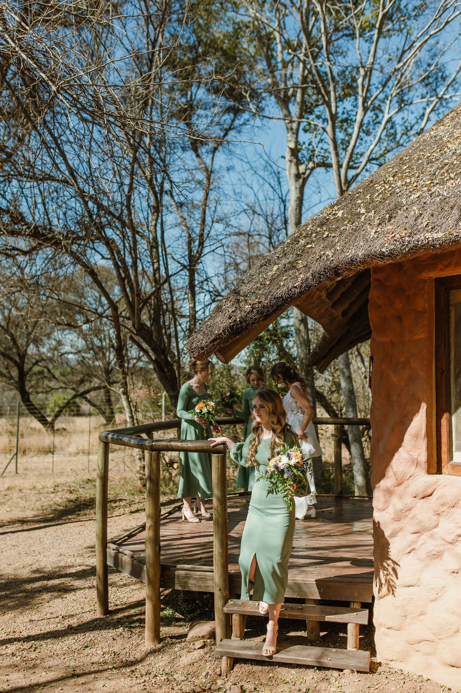 Traditional thatched-roof lodge with wooden deck in desert landscape.