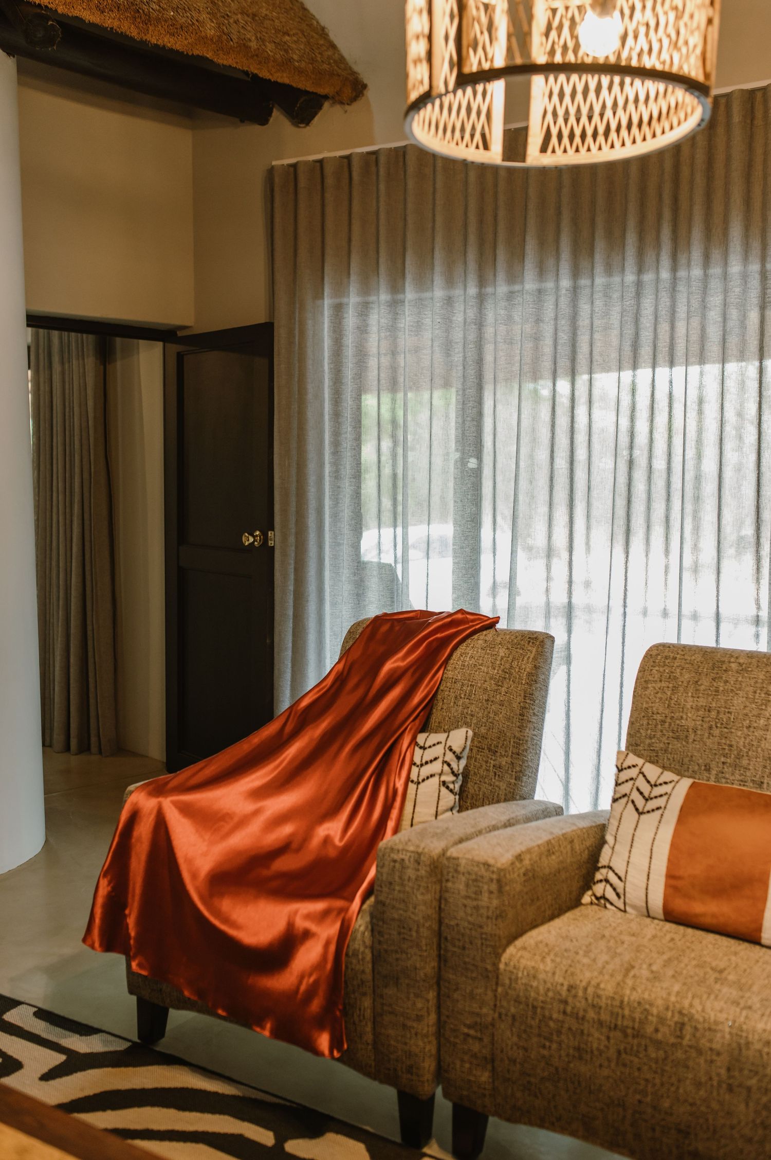 Cozy living room with brown couches and orange throw blankets under modern pendant lighting.