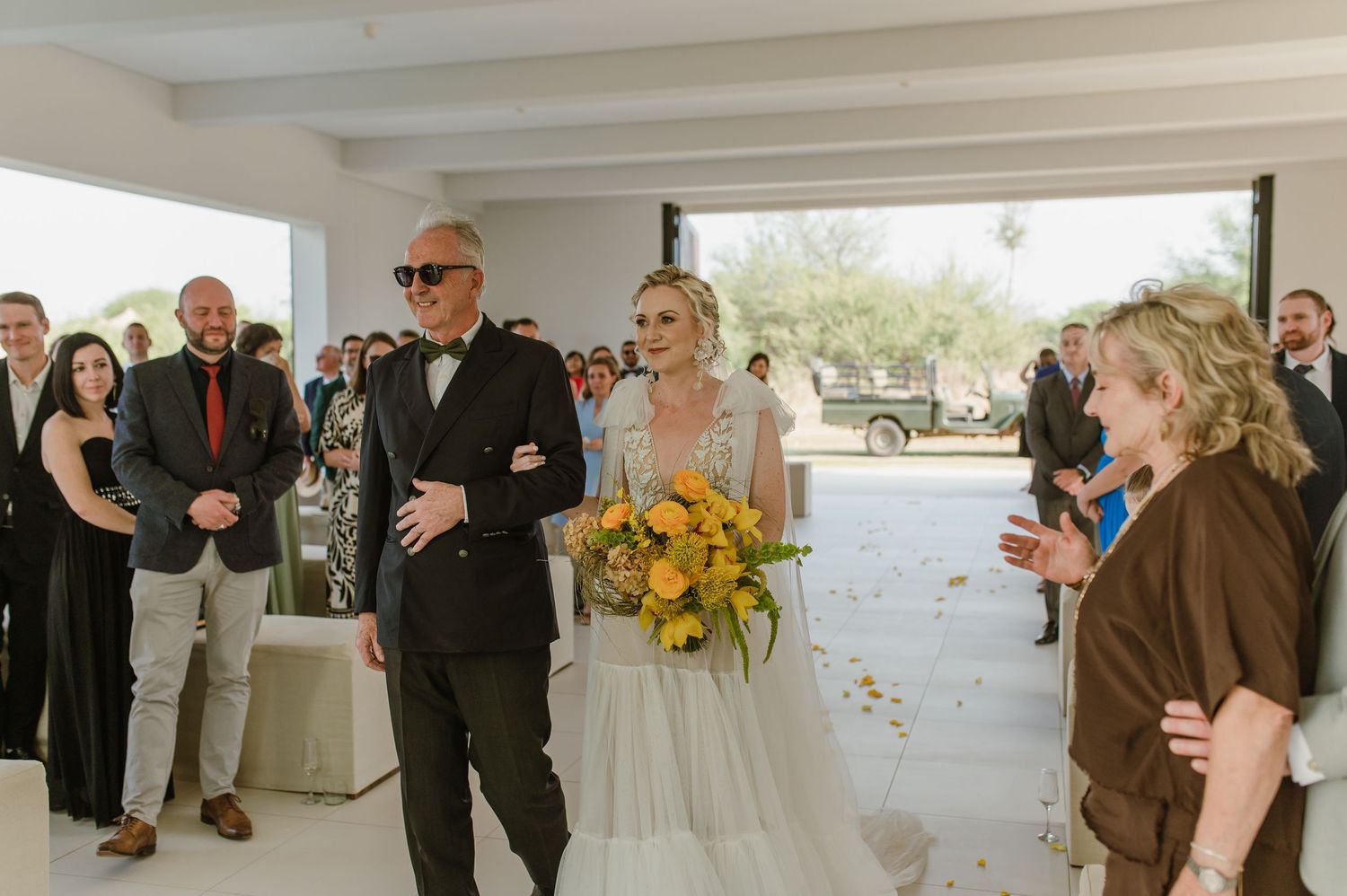 Wedding ceremony in progress in modern white space with yellow floral arrangements.