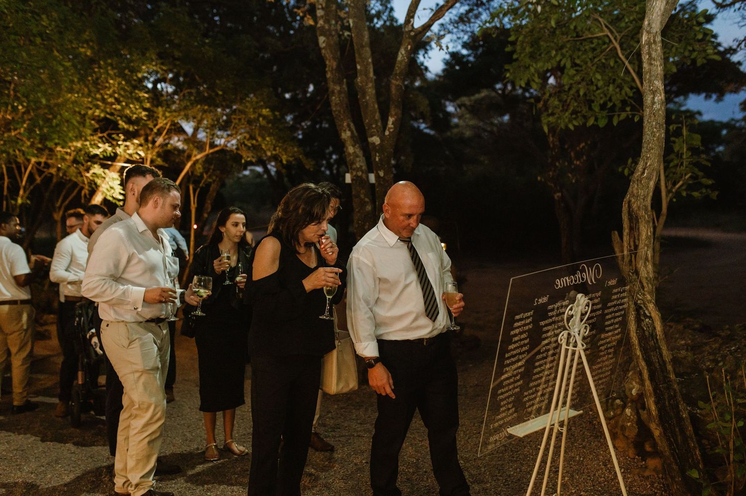 Nighttime gathering of guests enjoying an outdoor celebration under warm lighting.