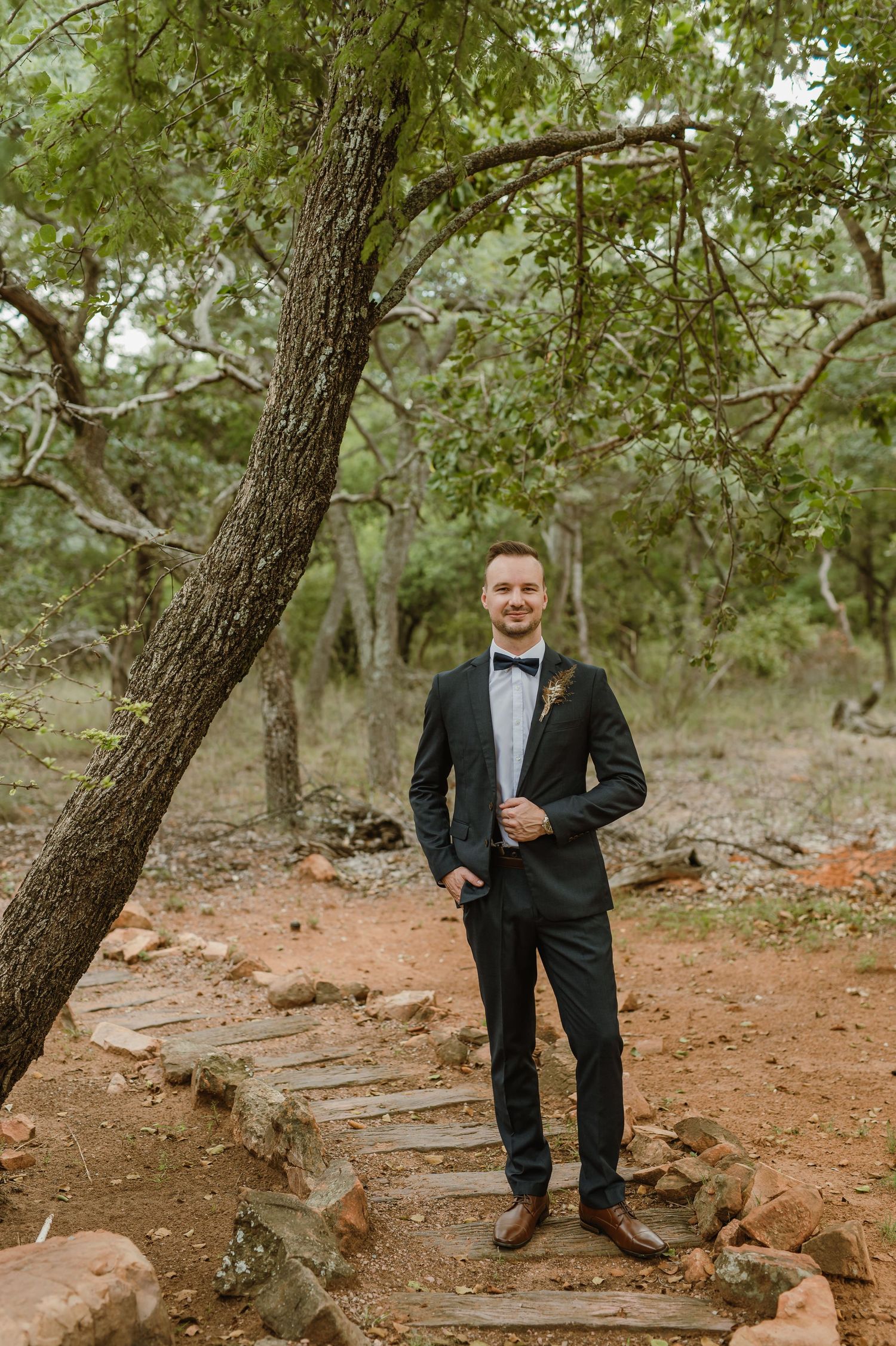 Formal attire photographed against a natural backdrop with trees and rocky ground.