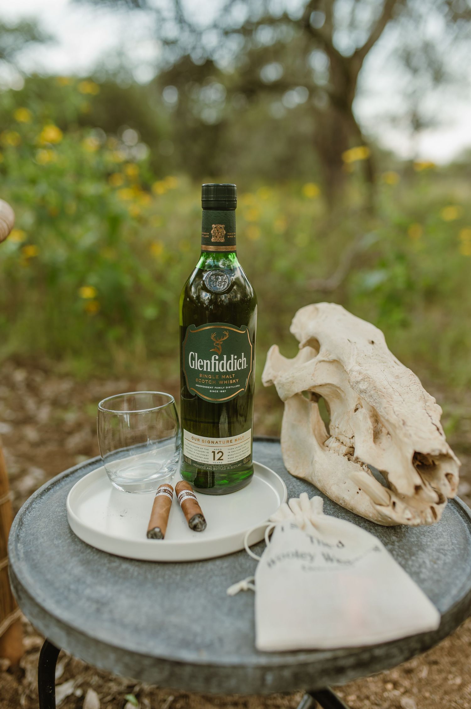 Glenfiddich whisky bottle and glasses arranged on stone surface with decorative elements.