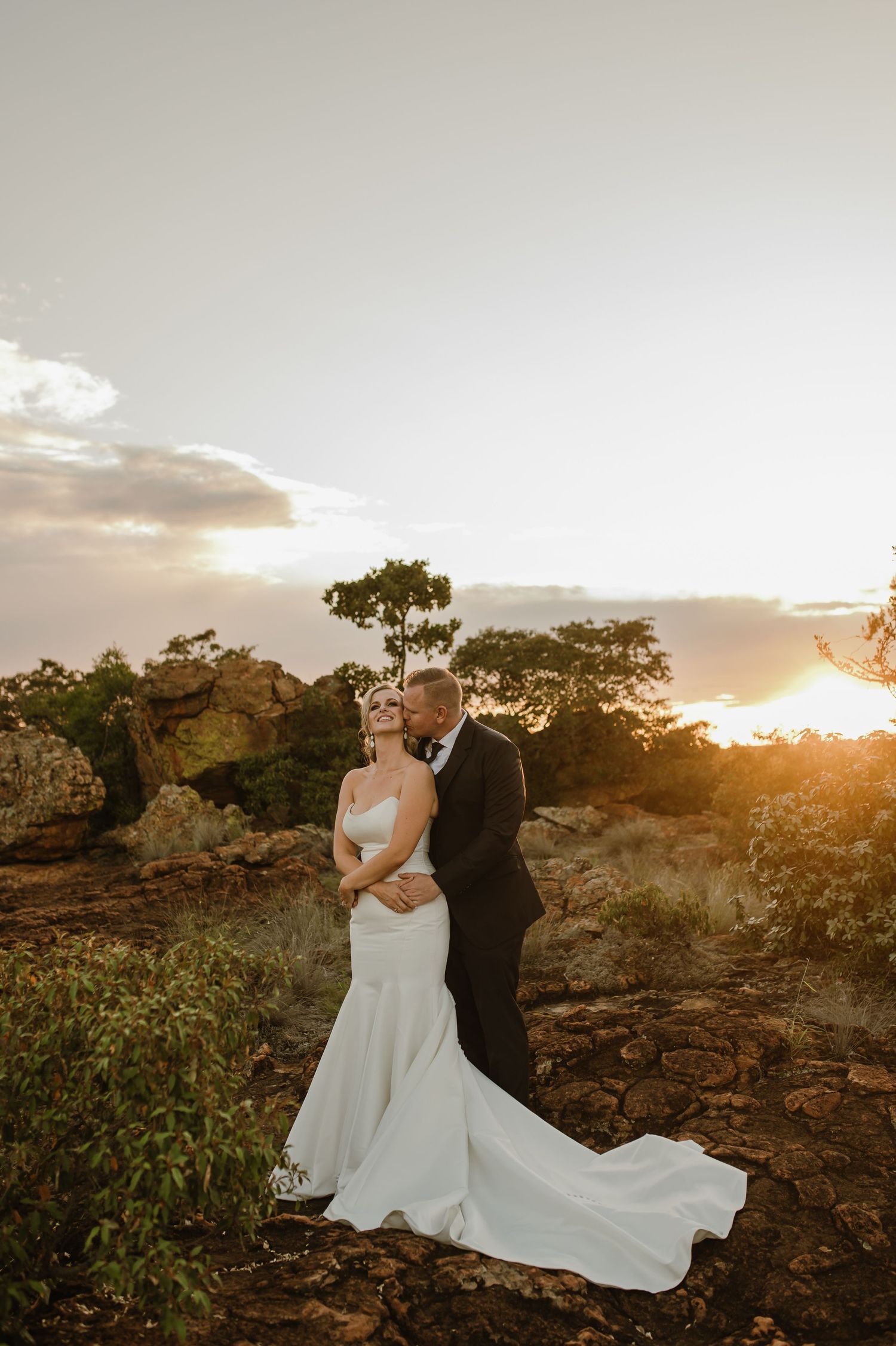 Sunset wedding photography captures couple in elegant attire against desert backdrop.
