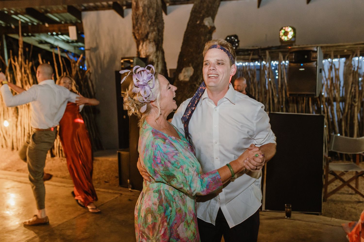 Couples dancing together at rustic wedding reception with bamboo wall decorations.