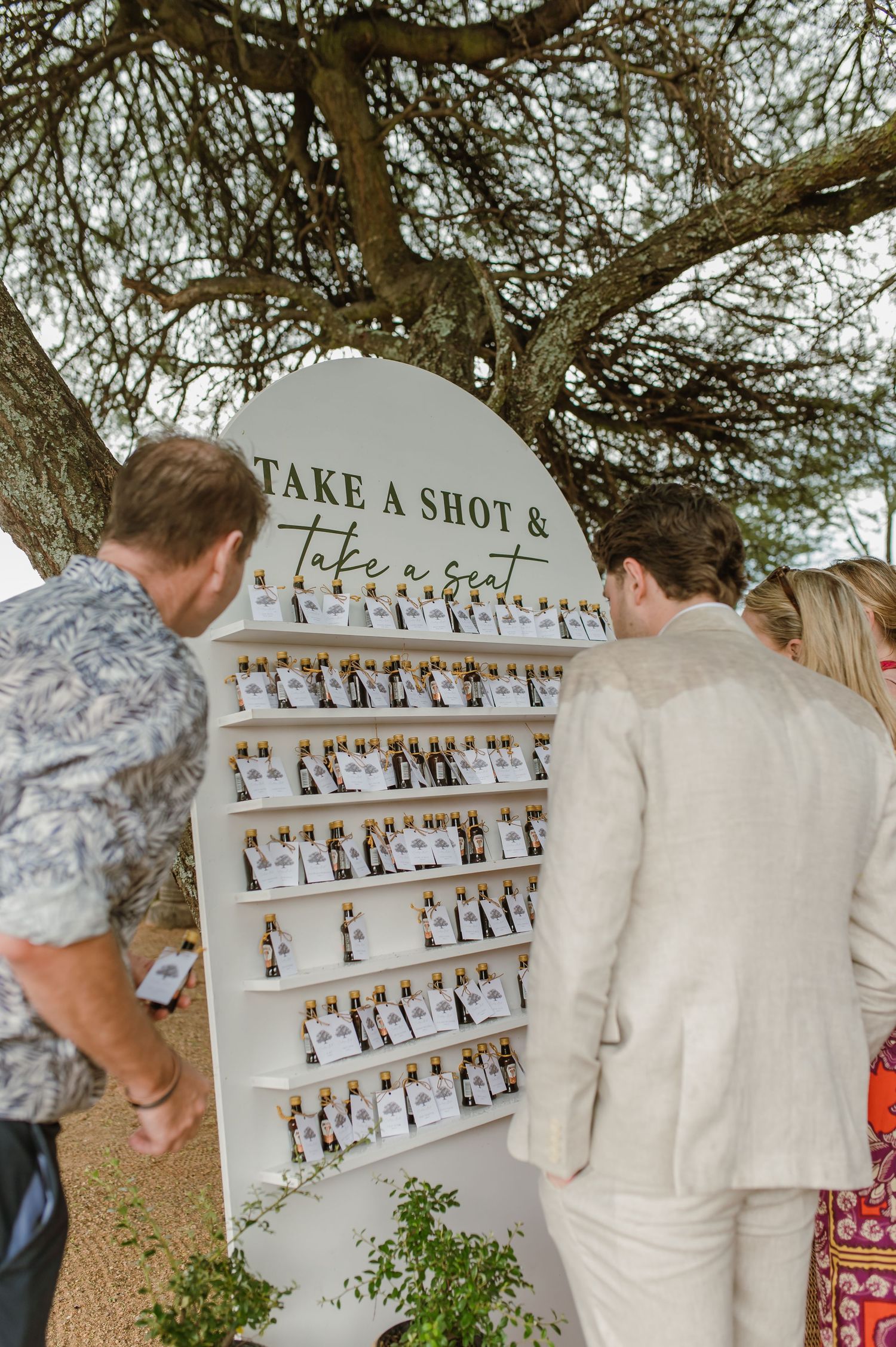 Wedding guests interact with a photo display wall featuring multiple shots arranged in a grid pattern.