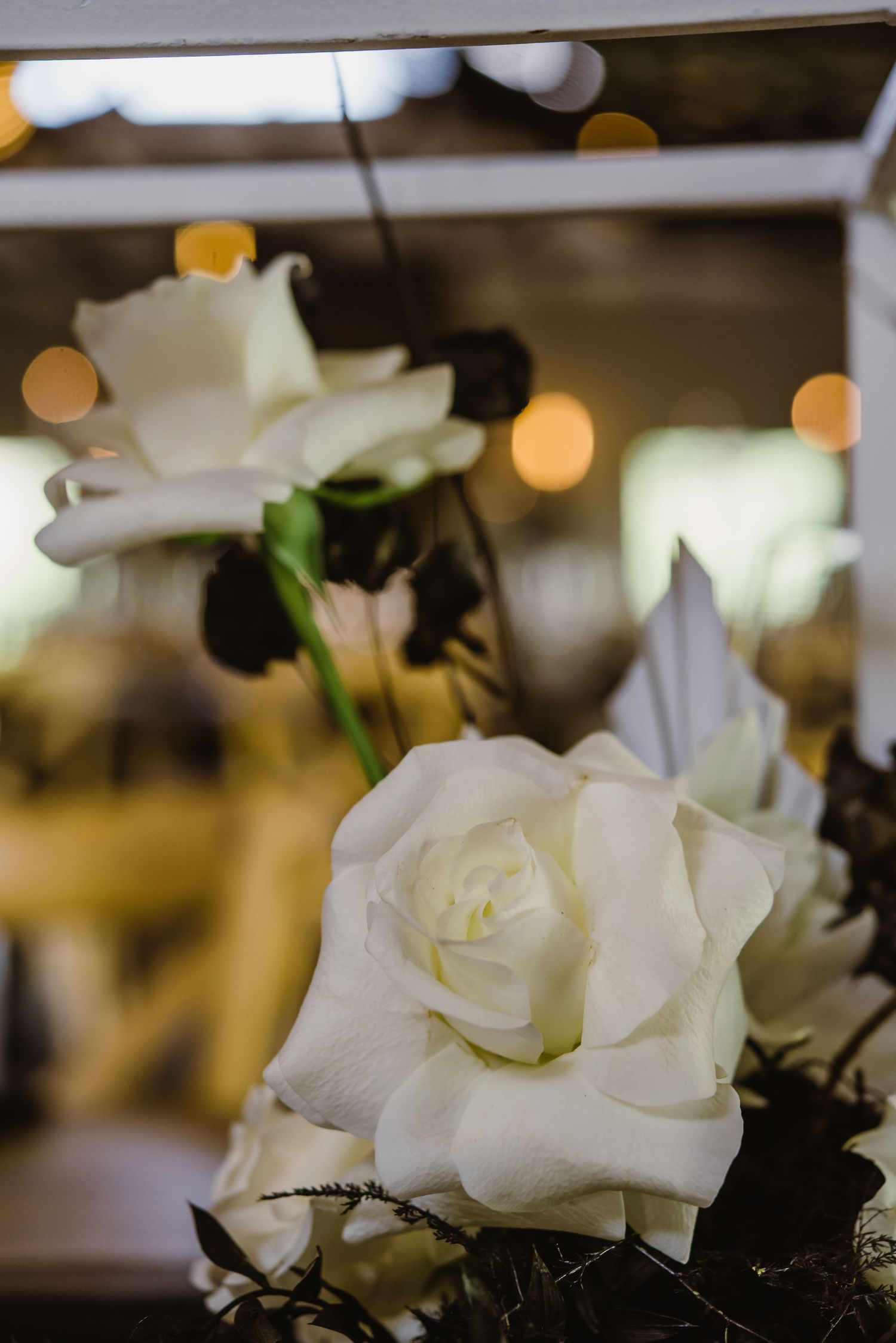 Delicate white roses with bokeh lights create romantic wedding table decorations.