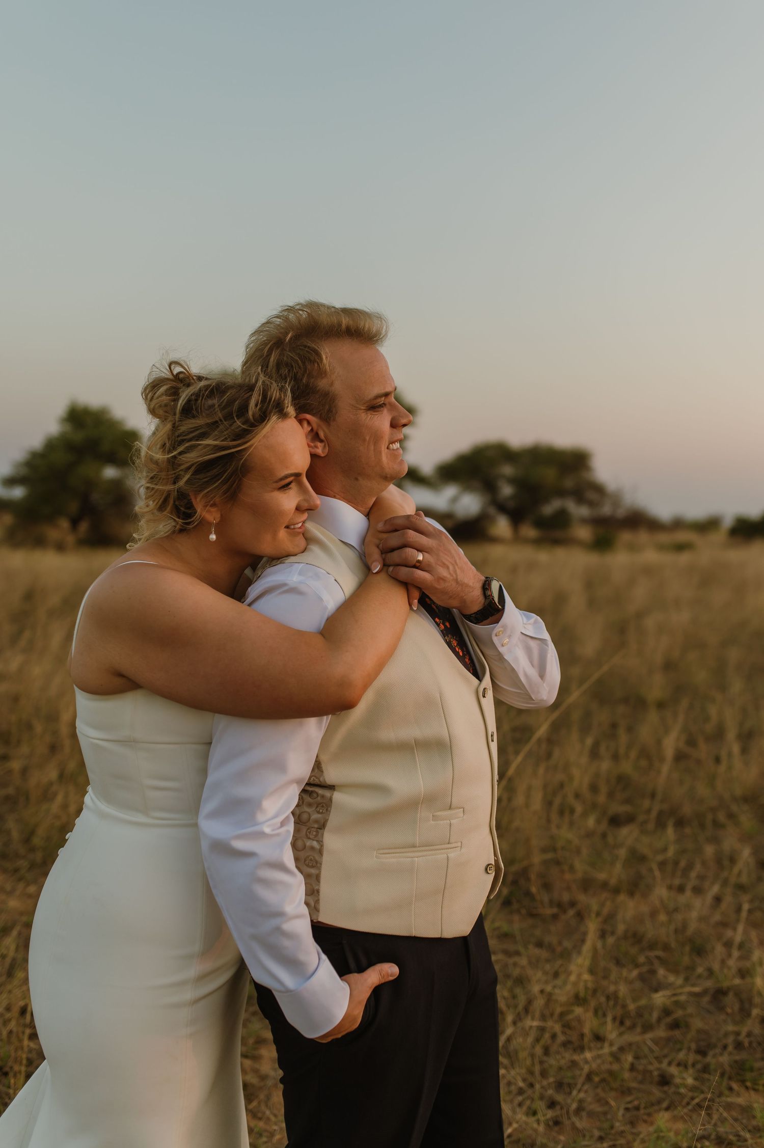 Intimate embrace between newlyweds in golden evening light.