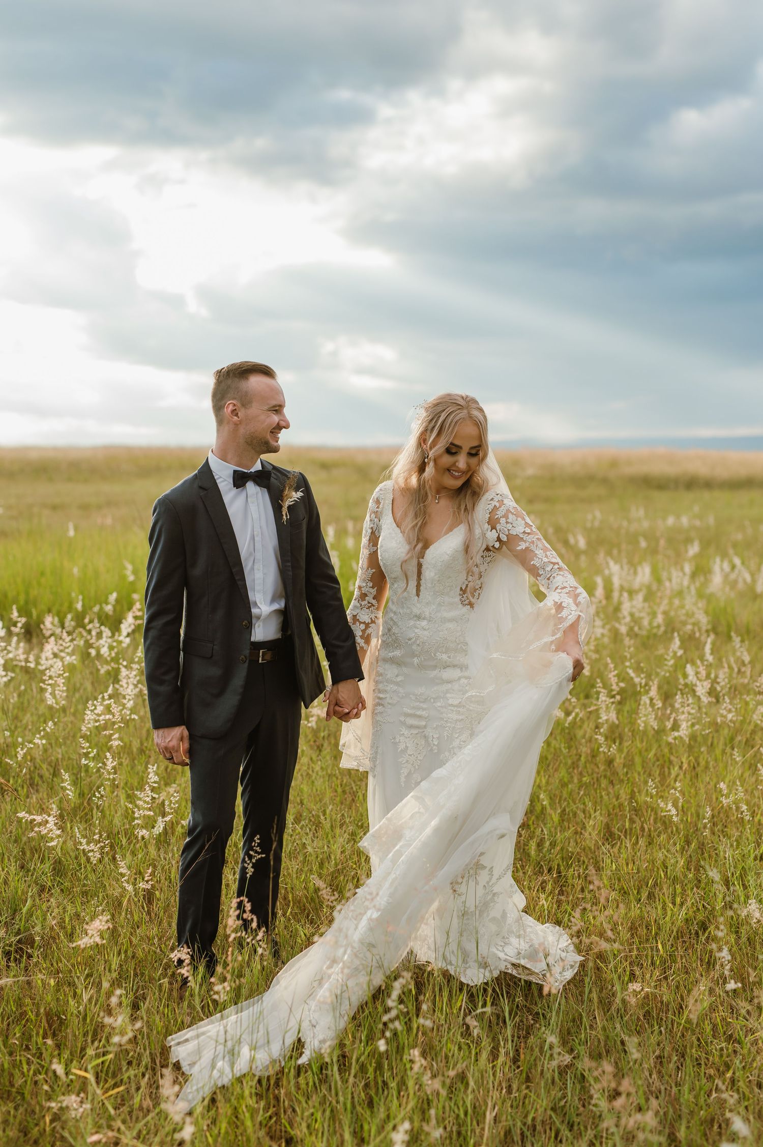Couple walking through a wildflower field with flowing wedding dress catching the breeze.