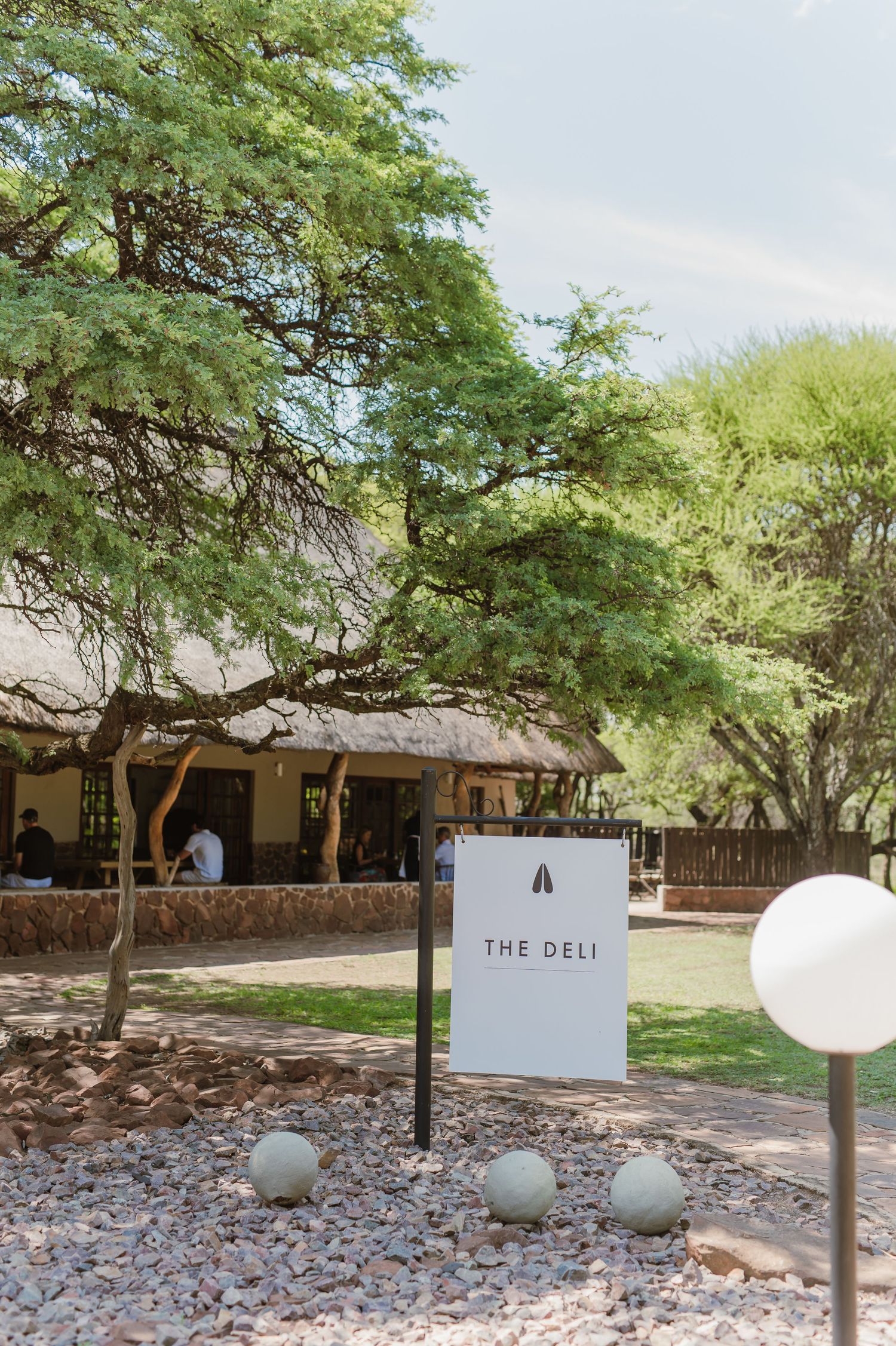 Outdoor venue signage for The Deli with decorative spherical lights and desert landscaping.