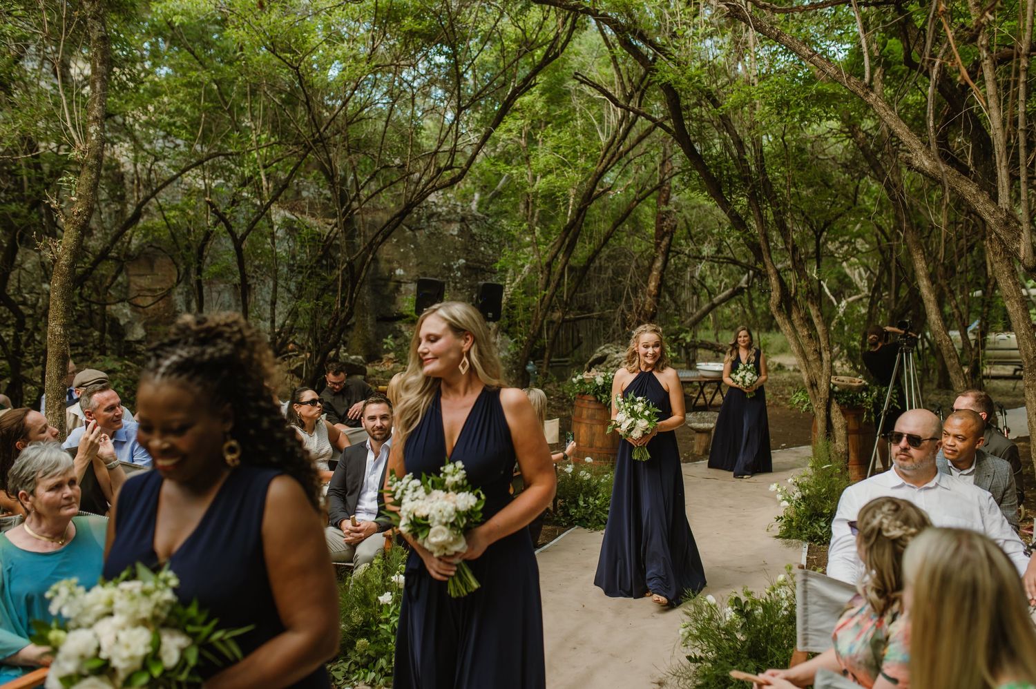 Wedding attendees gathered in a shaded woodland area for an intimate ceremony.