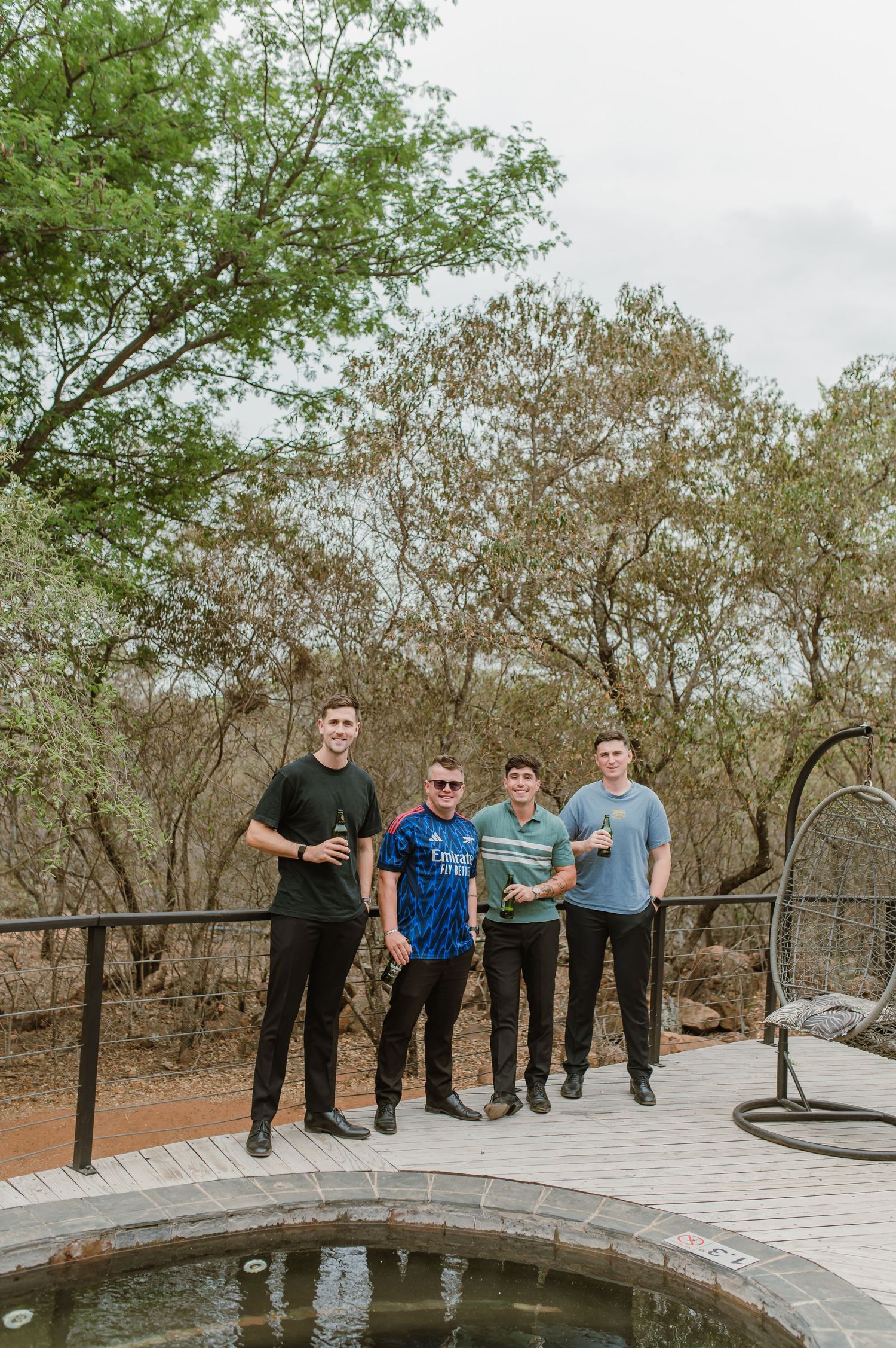 Friends gathered on a wooden deck overlooking a circular water feature in a natural setting.