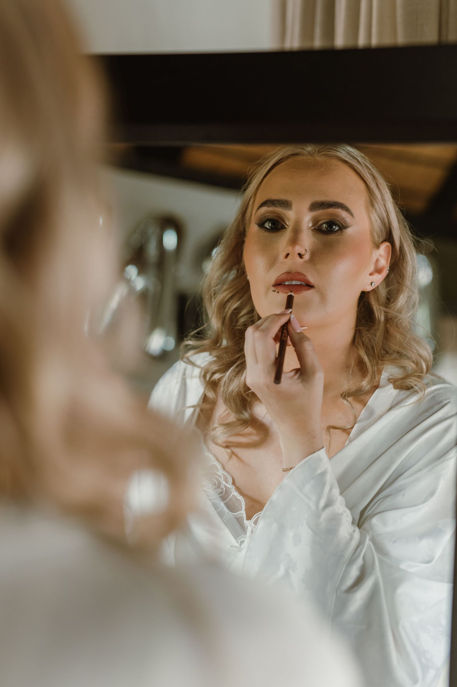 Bridal preparation scene reflected in mirror with soft lighting.