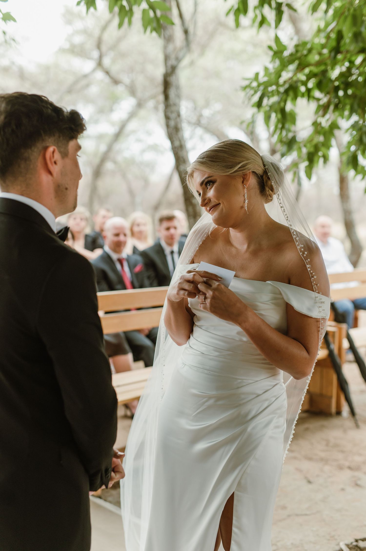 Intimate wedding ceremony moment shared between couple under a canopy of green leaves.