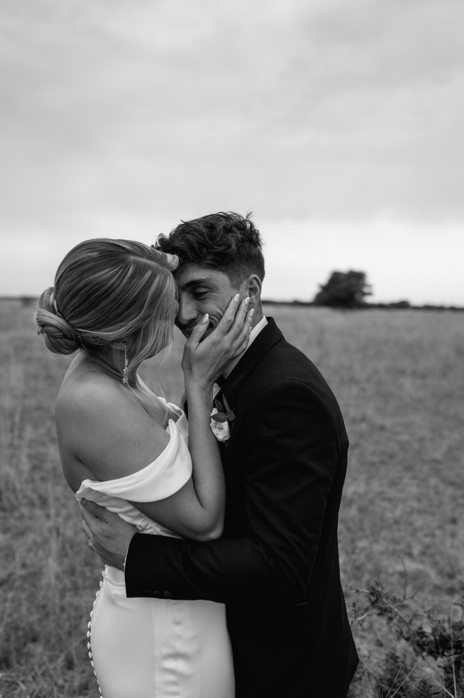 Black and white wedding portrait captures romantic moment in open field.