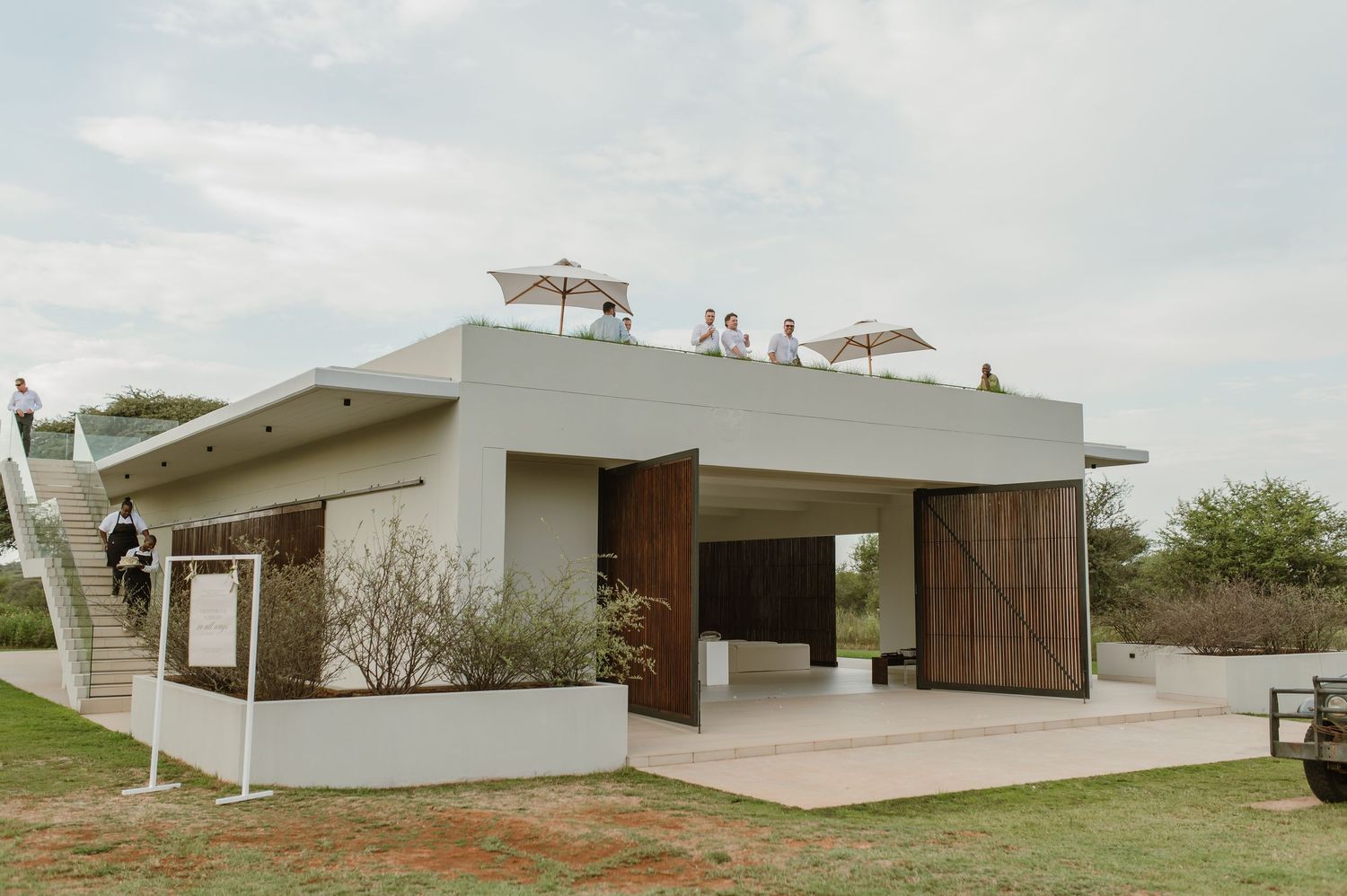 Exterior view of a modernist white house with clean lines and large windows set against a cloudy sky.